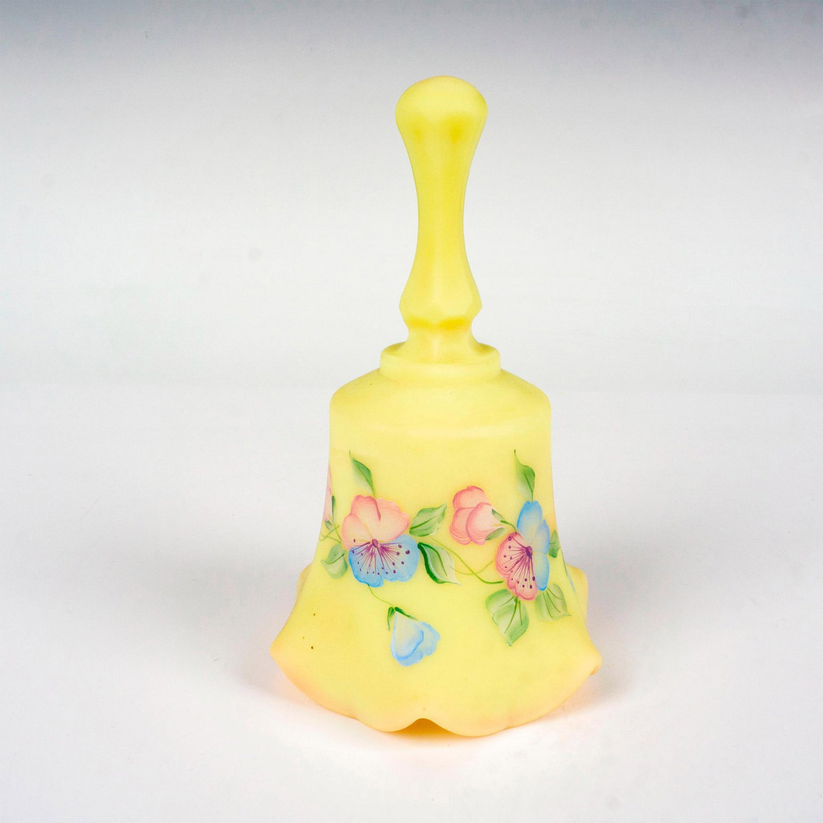 Fenton Burmese Glass Signed Bell: Lovely art glass bell in satin finish. This beautiful bell features a hand painted blue and purple floral band with its foliage. Signed C. Griffiths to interior. Artist: C. Griffiths Issued: c. 1970 D