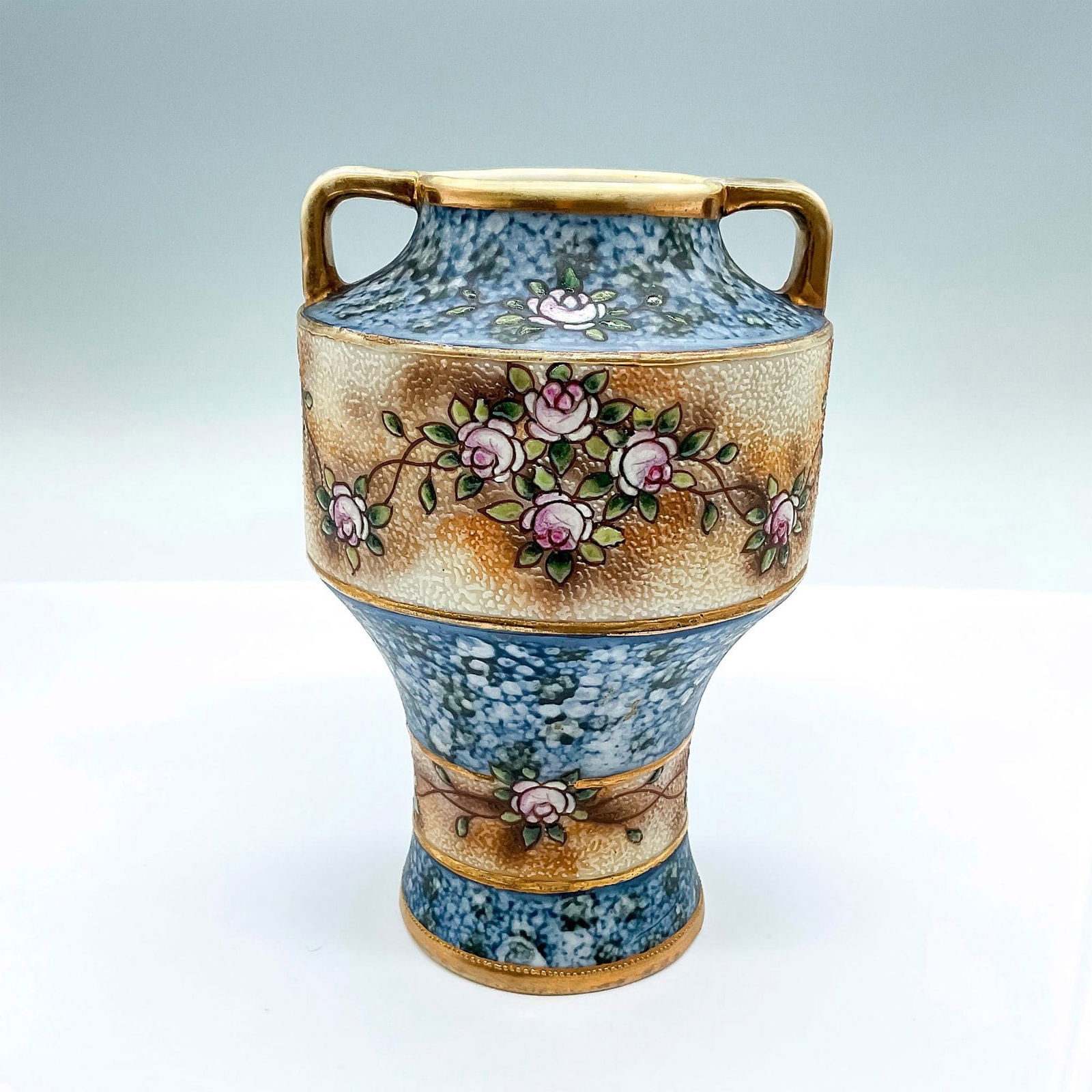 Vintage Noritake Porcelain Vase: A small blue and brown tone vase adorned with pink roses. Noritake backstamp. Dimensions: 4.25"W x 6.25"H Manufacturer: Noritake Country of Origin: Japan