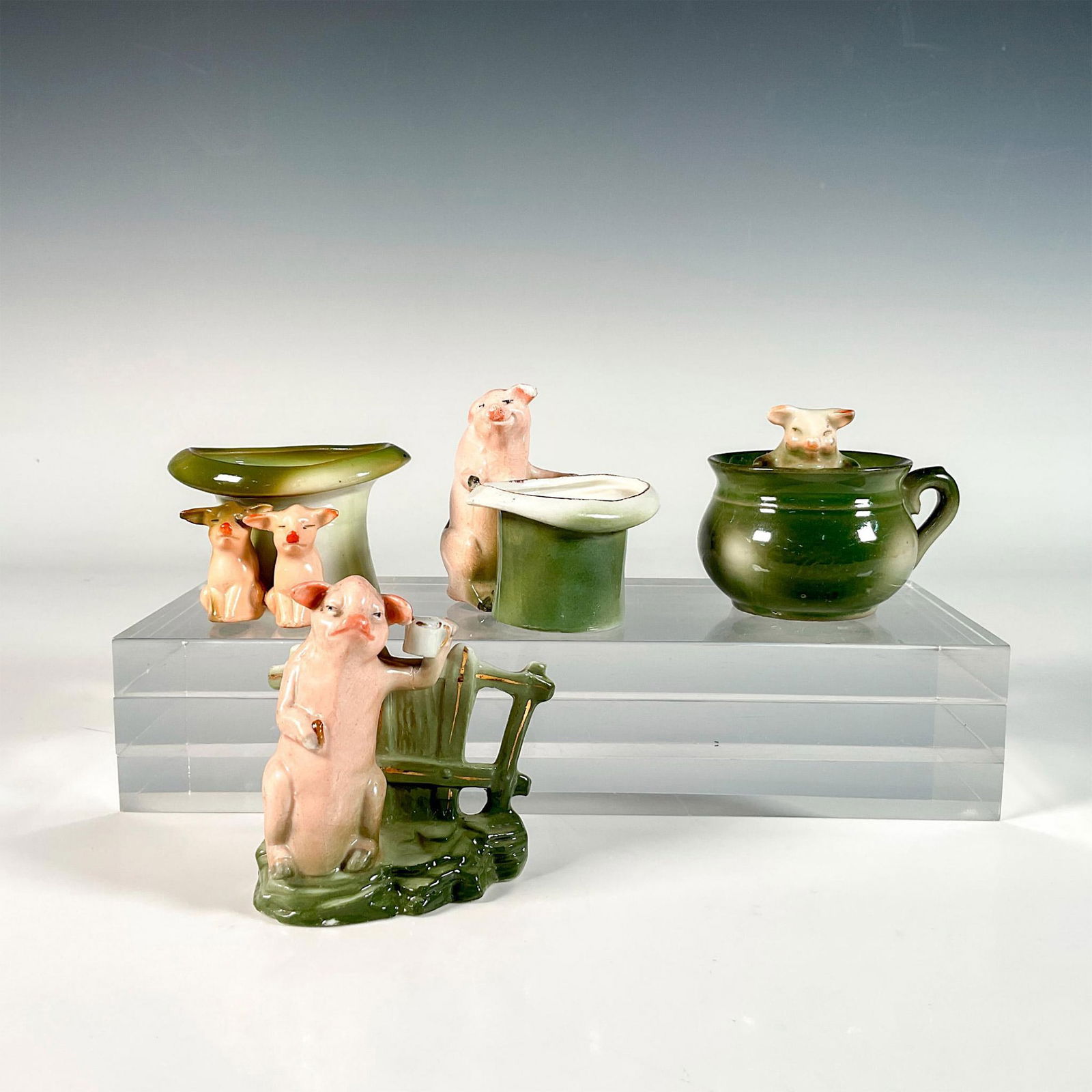 4pc German Porcelain Figural Toothpick Holders: Absolutely charming set including two pink pigs sitting in front of a top hat shaped holder, a pig in a chamber pot, a pig raising a mug, and a pig standing on two legs by a top hat. Painted in green