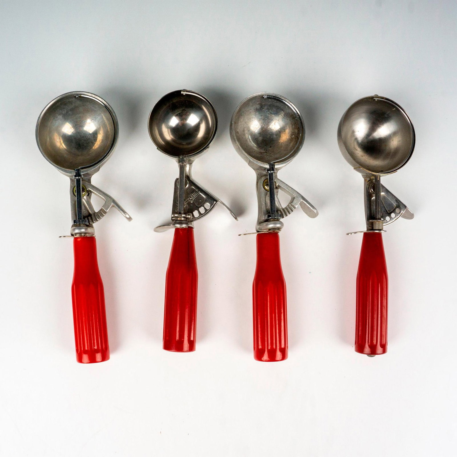 4pc Vintage Red Bakelite Ice Cream Scoops: This vintage grouping of ice cream scoops includes #20 Shore Craft, #12 Maid of Honor, #12 Peerless, and #16 unmarked ice cream scoops all with stainless steel parts and red Bakelite handles. All scoo