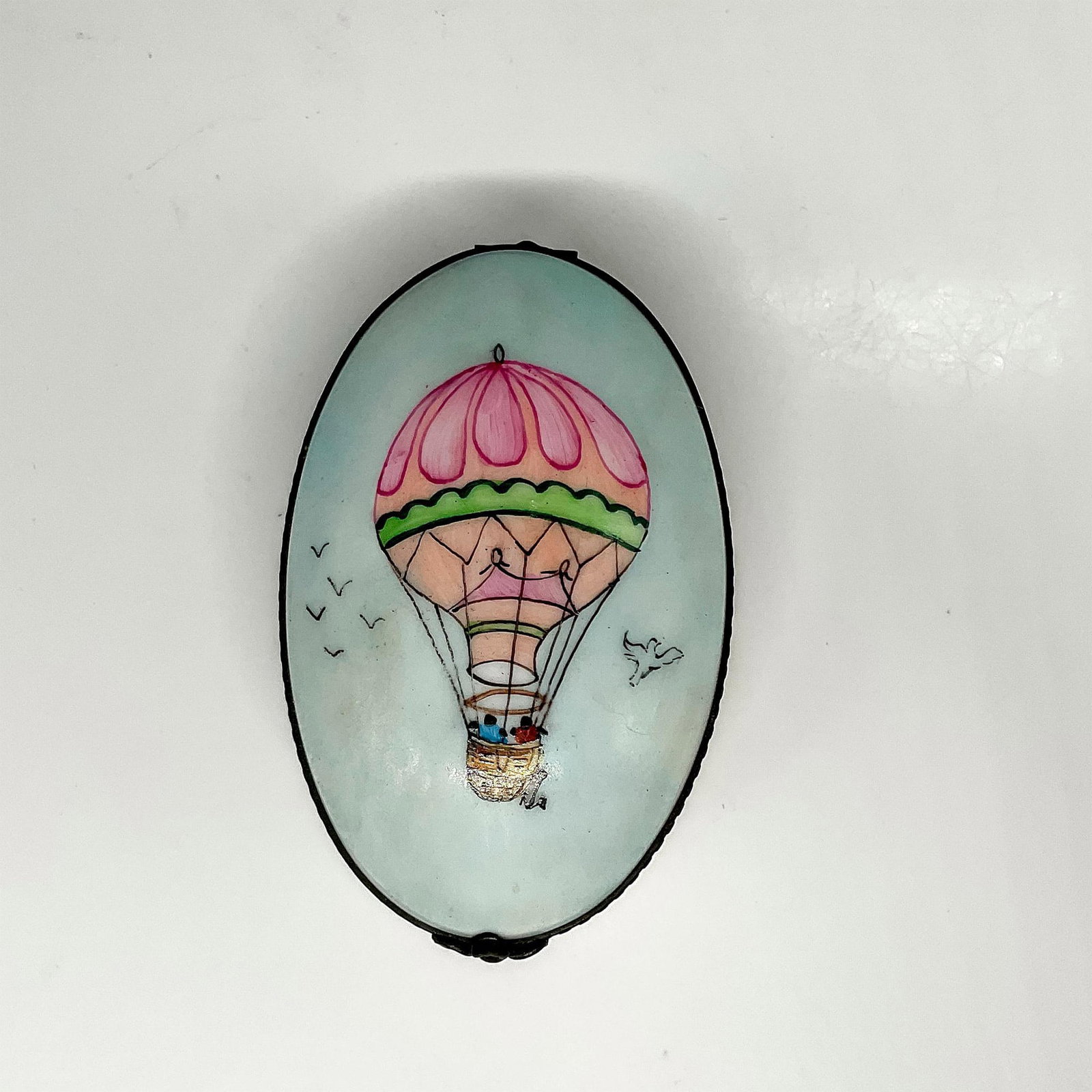 Rochard Porcelain Box, Hot Air Balloon Ride: Oval porcelain box hand-painted in Limoges, France. Features a couple in a hot air balloon on the lid with a desert landscape encircling the body of the box. B S+J Hand Painted for Rochard written on 