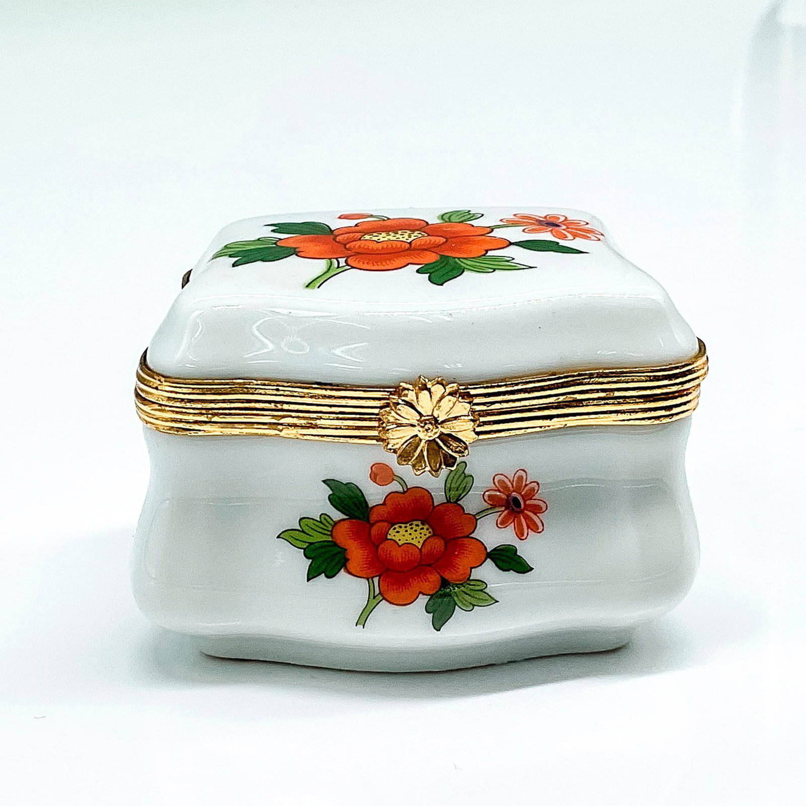 Limoges Porcelain Trinket Box: Hand painted orange floral design with gilded metal closure band and floral clasp. Limoges backstamp. Issued: 20th century Dimensions: 2.5"L x 2"W x 1.75"H Manufacturer: Limoges Country of Origin: Fra