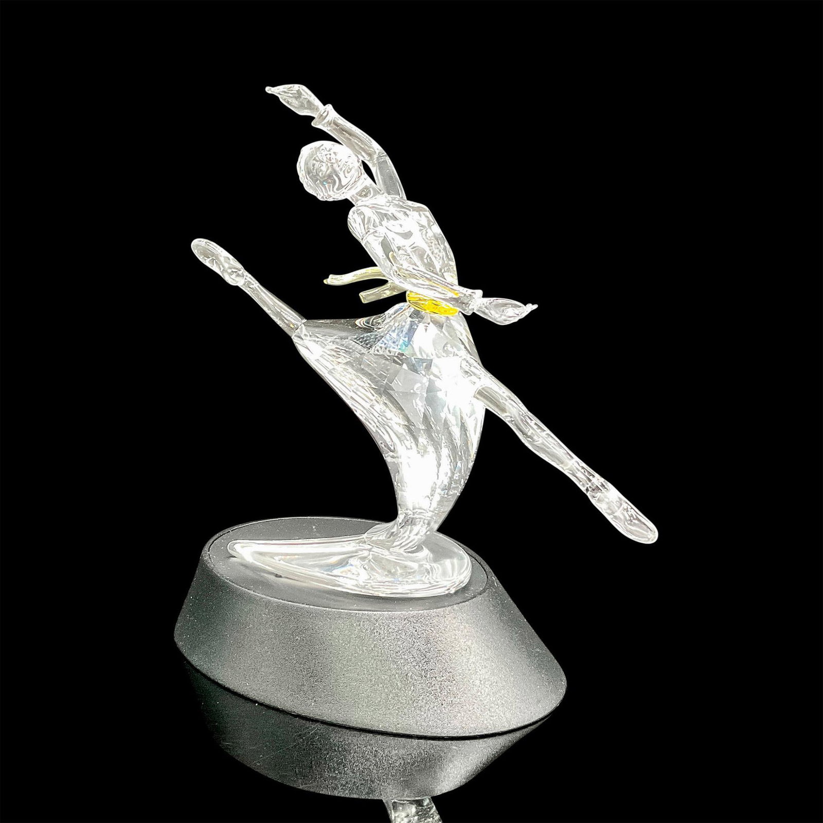 Swarovski Crystal Figurine, Magic of Dance Anna 2004: Part of the Magic of Dance trilogy. Clear, faceted figural in dance pose representing famous ballerina, Anna Pavlova. Yellow crystal sash adorns clear figural. Swarovski backstamp. 7400 200 400. This 