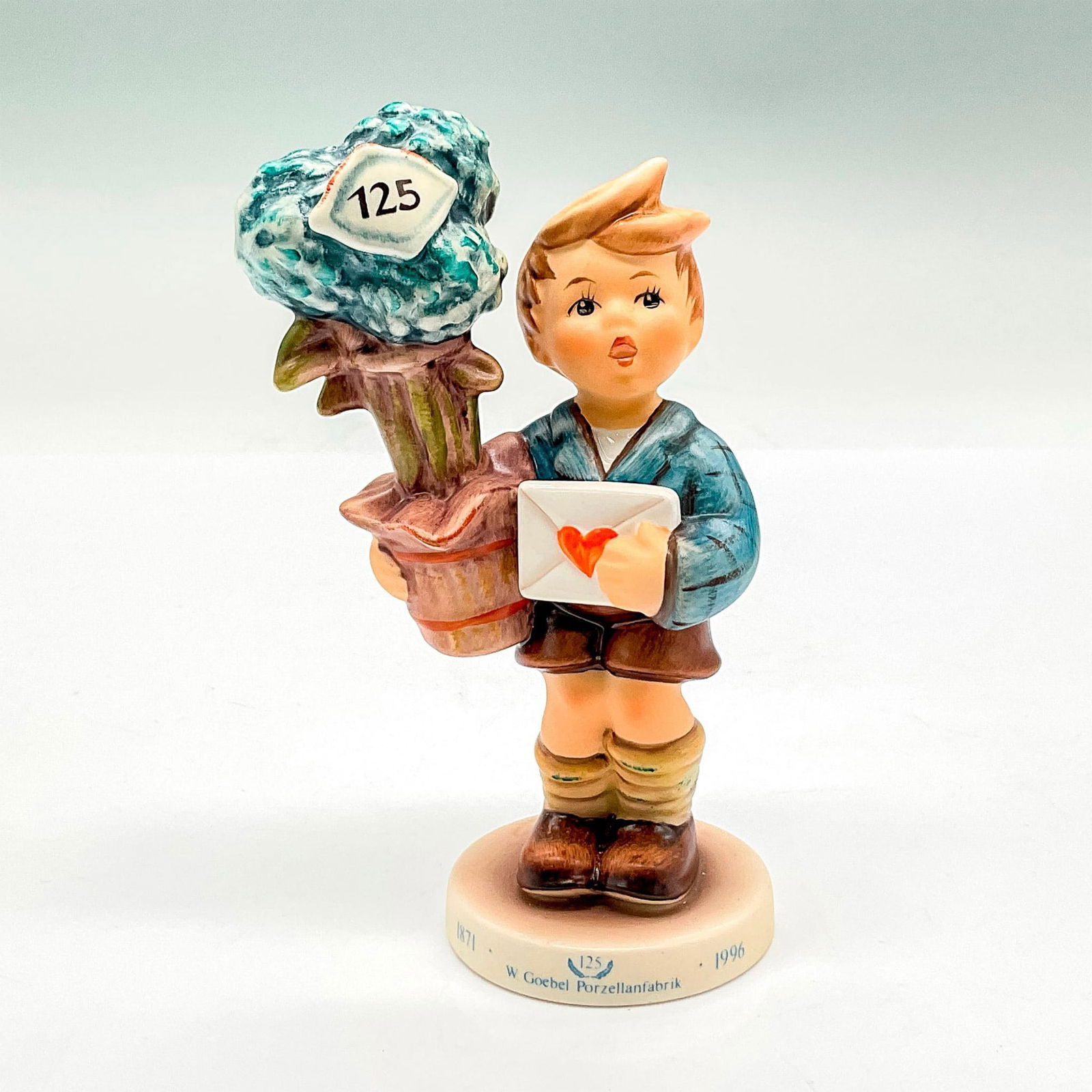 Goebel Hummel Porcelain Figurine, Good News HUM 539: Hand painted figure of a young boy holding a potted plant and a letter. Goebel backstamp. This item has its original box: 7.5"L x 5"W x 3.75"H. Certificate of Authenticity included. Issued: 20th c. Di