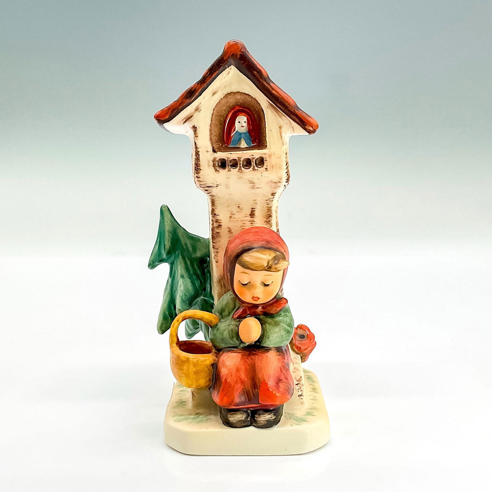 Goebel Hummel Porcelain Figurine, Worship HUM 84/0: Hand painted figure of a young girl sitting in front of a tower with hands clasped in a prayerful pose. Goebel backstamp. This item has its original box: 7.5"L x 5"W x 4"H. Issued: 1991 Dimensions: 2.