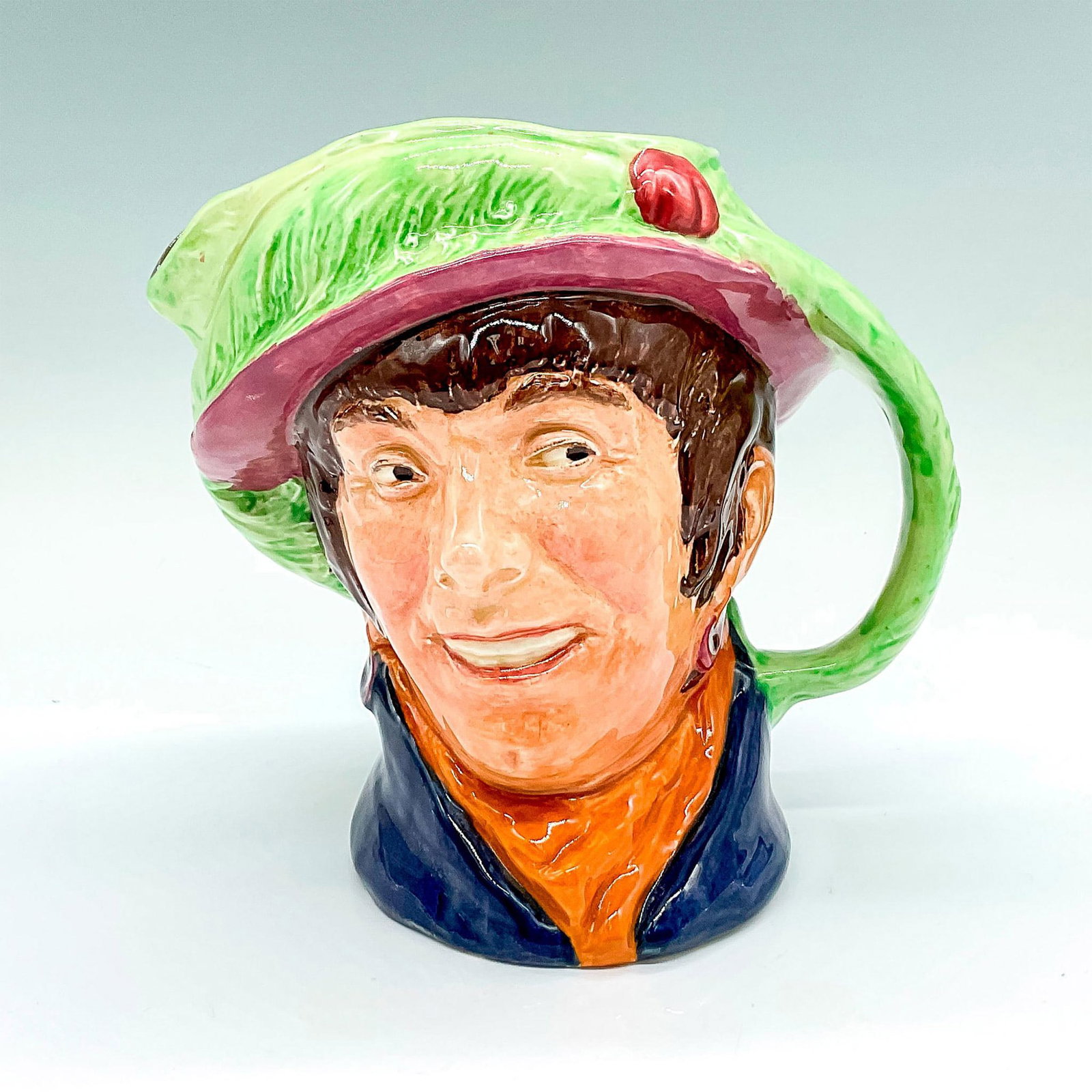 Pearly Girl D6208 Colorway Royal Doulton Large Character Jug: Green and pink hat, blue coat, and orange scarf. Royal Doulton backstamp. Artist: Harry Fenton Issued: c. 1947 Dimensions: 6.5"H Manufacturer: Royal Doulton Country of Origin: England