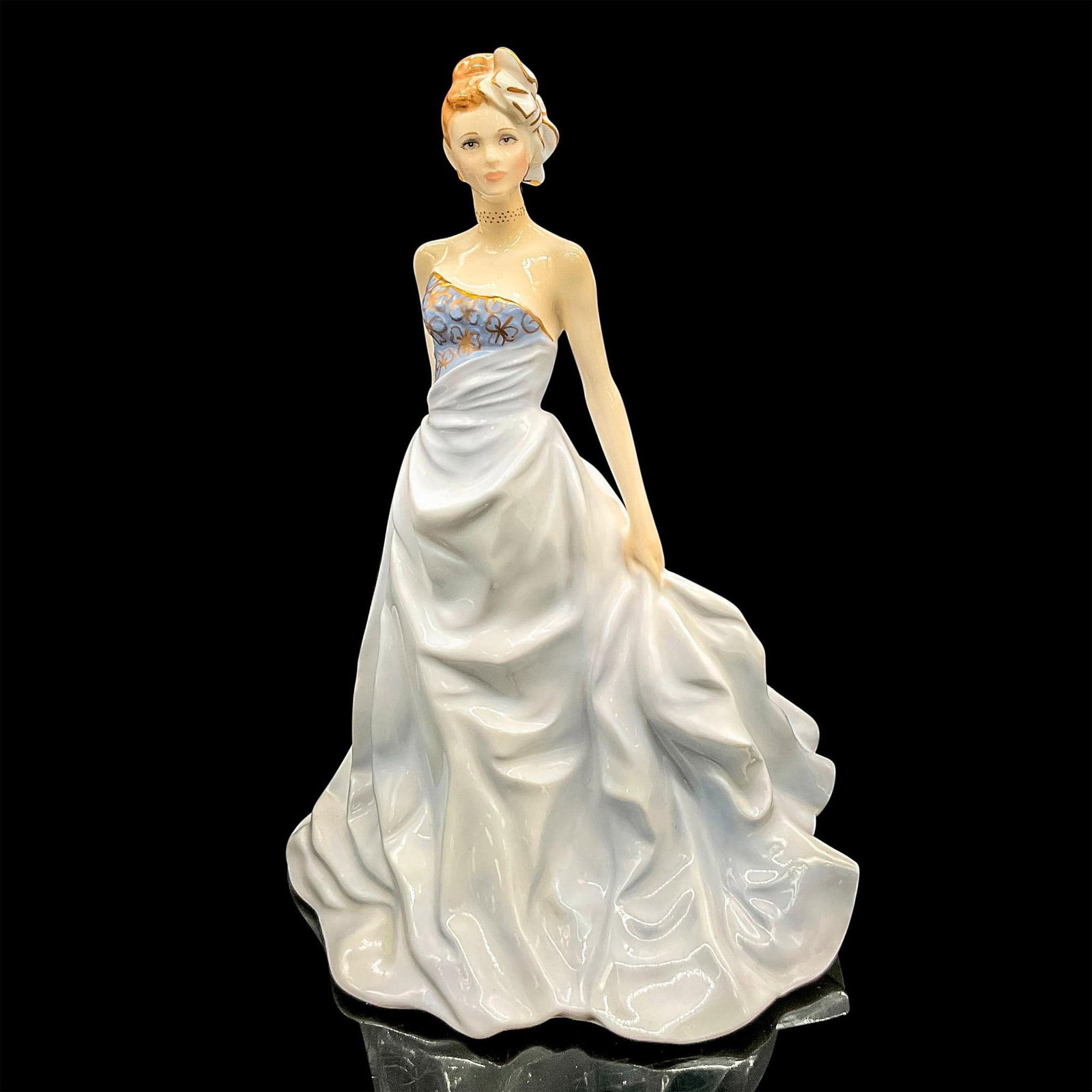 Royal Worcester Figurine, Isabelle: Bone china figure of a refined lady in a pale blue gown with gold accents and a bow in her hair. Royal Worcester backstamp. Figurine of the Year 1998. Dimensions: 6"L x 5.25"W x 8.75"H Manufacturer: R
