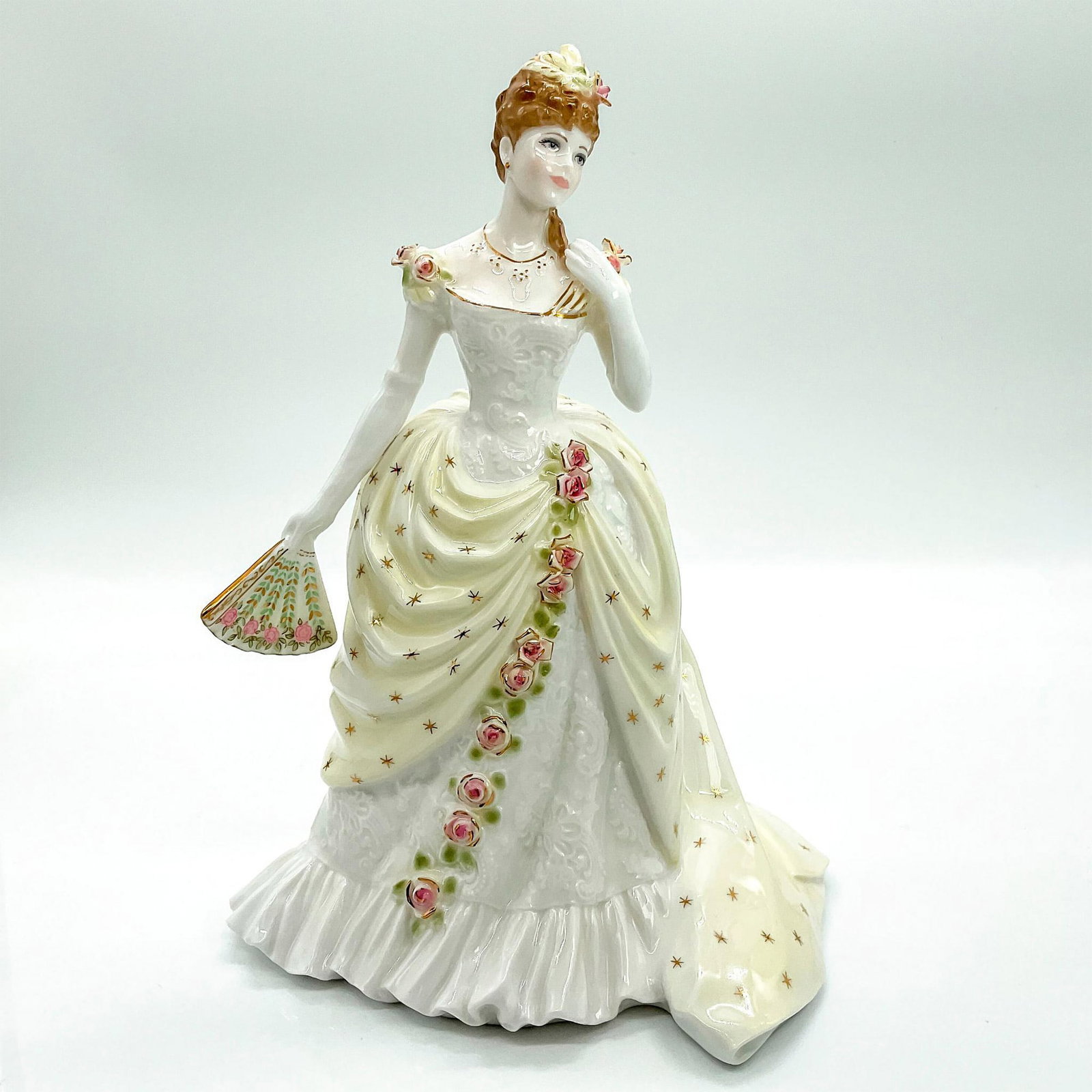 Royal Worcester Figurine, The Embassy Ball: Limited edition fine bone china that is part of the Splendour At Court Collection. Depicts beauty in a light yellow and white floral dress with matching hair pin and hand fan; stunning gold gilt touch