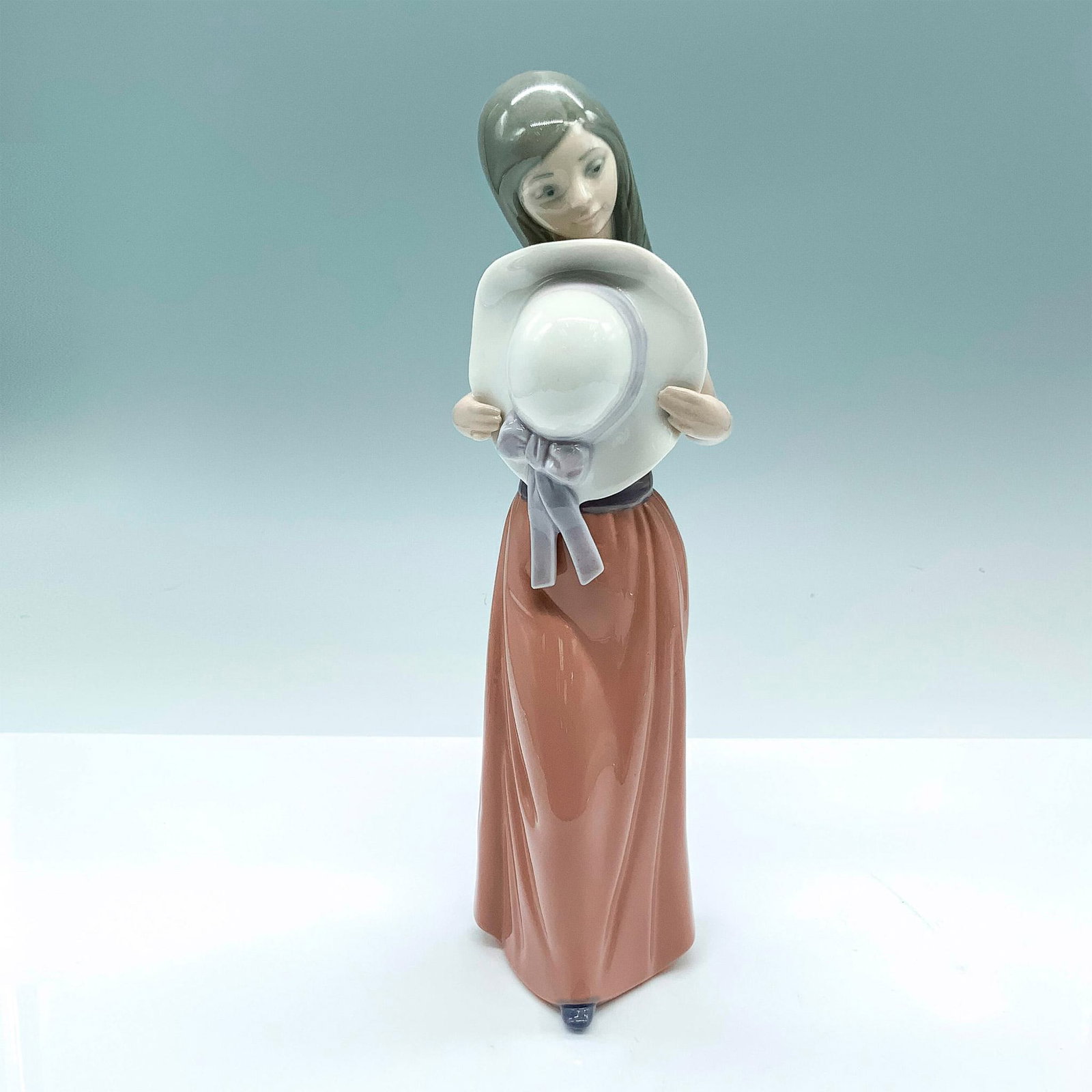 Bashful 1005007 - Lladro Porcelain Figurine: Glossy finish; Lladro backstamp. Artist: Francisco Catala Issued: 1978 - 1997 Dimensions: 9.75"H x 3.25"W Manufacturer: Lladro Country of Origin: Spain