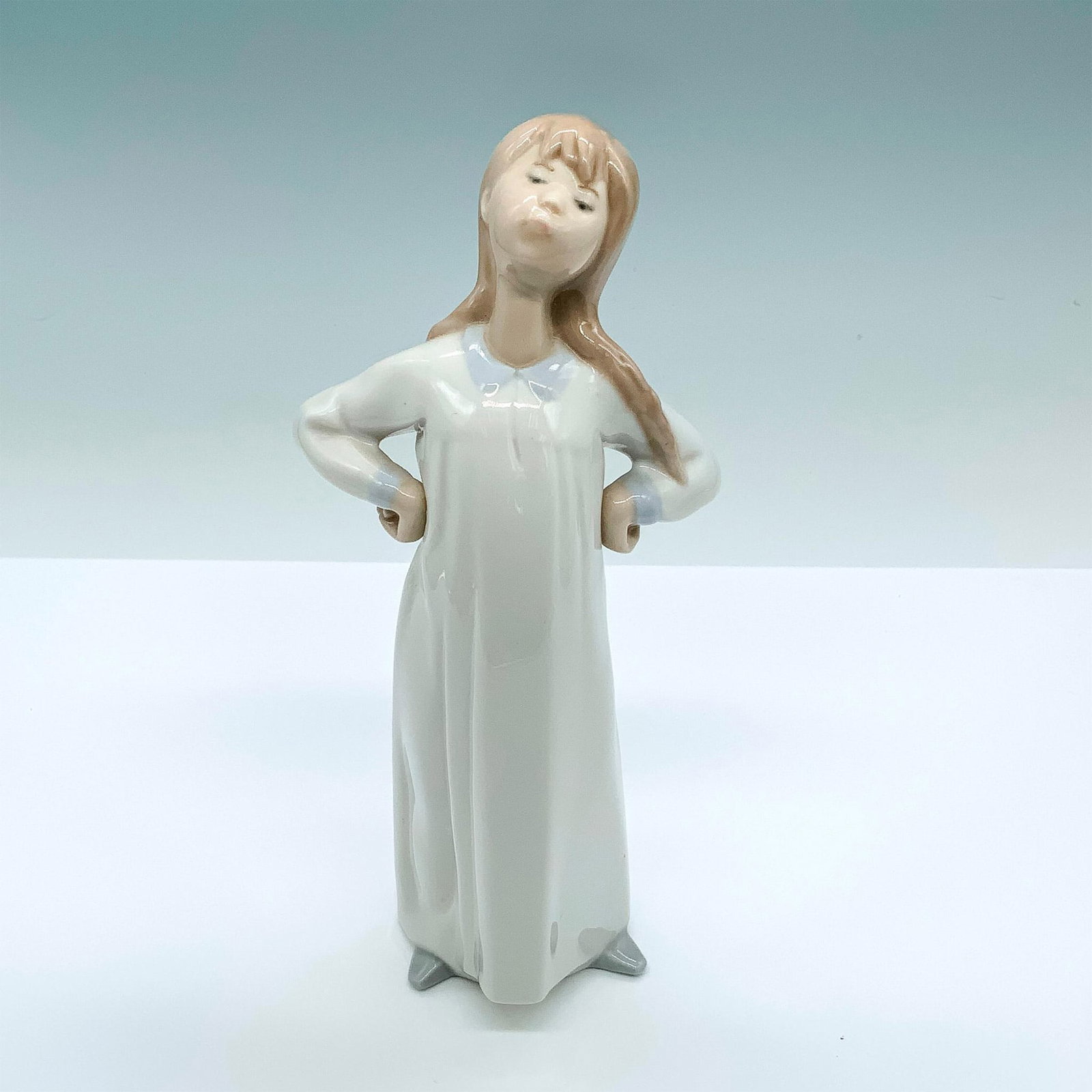 Girl Stretching 1004872 - Lladro Porcelain Figurine: Glossy finish; Lladro backstamp. Artist: Fulgencio Garcia Issued: 1974 - 1999 Dimensions: 8"H Manufacturer: Lladro Country of Origin: Spain