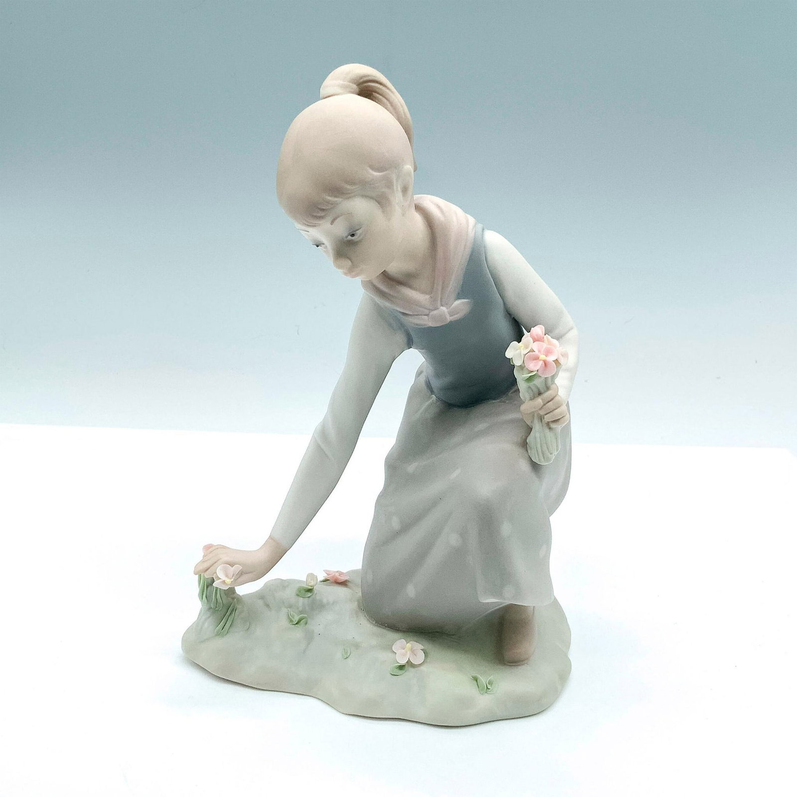 Girl With Flowers 1011172 - Lladro Porcelain Figurine: Matte finish; Lladro backstamp. Artist: Vicente Martinez Issued: 1971 - 1991 Dimensions: 8.25"H Manufacturer: Lladro Country of Origin: Spain