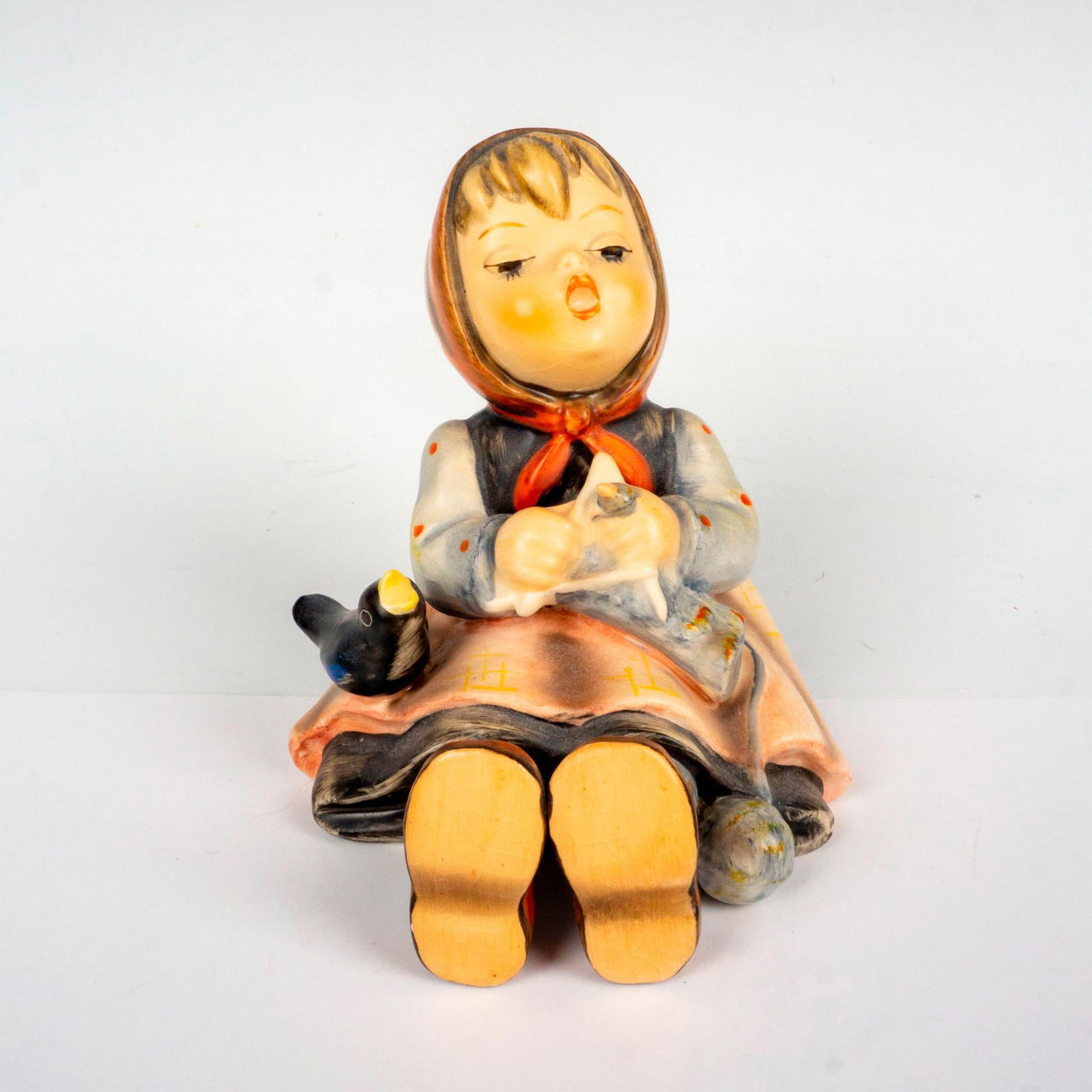 Goebel Hummel figurine, Happy Pastime HUM 69: Hand painted porcelain figure. Sitting girl knitting with bird by her side. Goebel backstamp. Artist: M.I. Hummel Issued: 1960-1972 Dimensions: 3.5"L x 3.25"W x 3.5"L Manufacturer: Goebel Hummel Coun