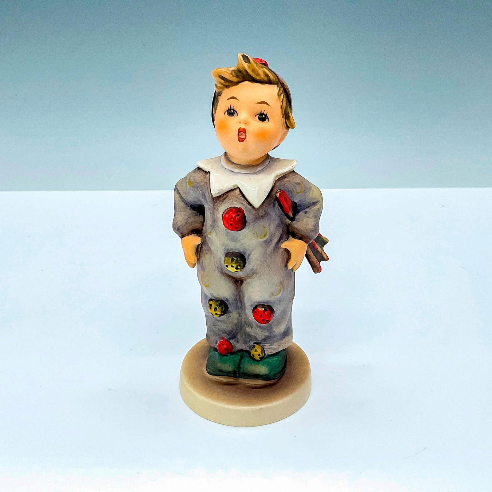 Goebel Hummel Porcelain Figurine, Clown Boy Hum 328: Goebel Hummel #328 Porcelain Carnival Boy Figurine in Jester Costume. Goebel backstamp. Issued: 20th century Dimensions: 2.5"L x 2.5"W x 5.5"H Manufacturer: Goebel Hummel Country of Origin: Germany