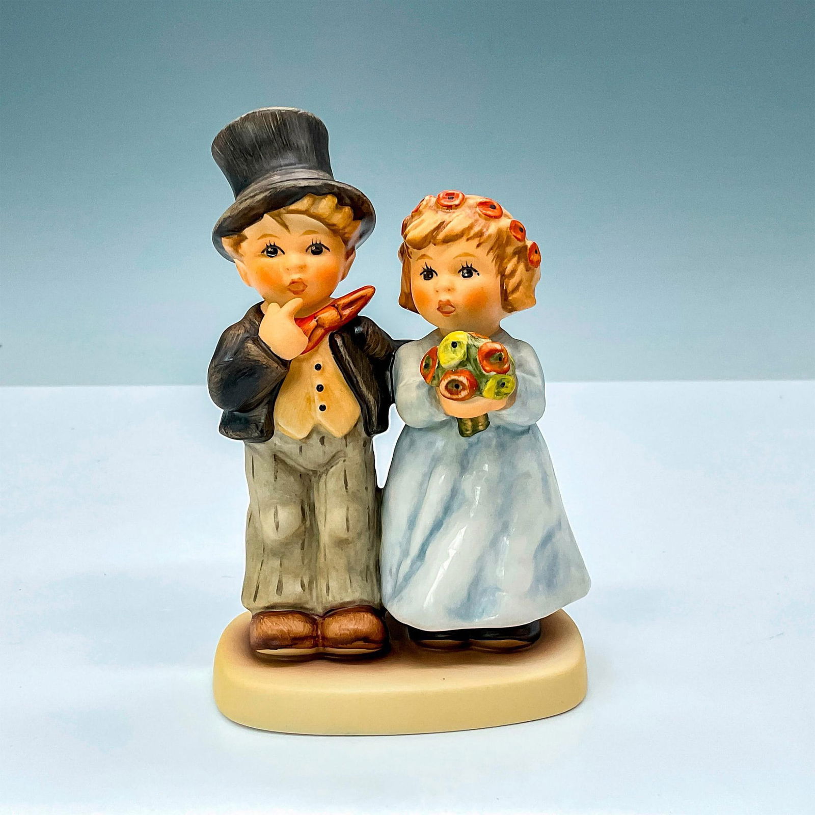 Goebel Hummel Porcelain Figurine, Dearly Beloved HUM2003: Hummel porcelain figurine HUM2003 depicts boy in suit and girl in blue dress with flowers. Goebel backstamp TM8. M. I. Hummel impressed backstamp. #wedding #goebel Issued: 2000-2009 Dimensions: 3"L x