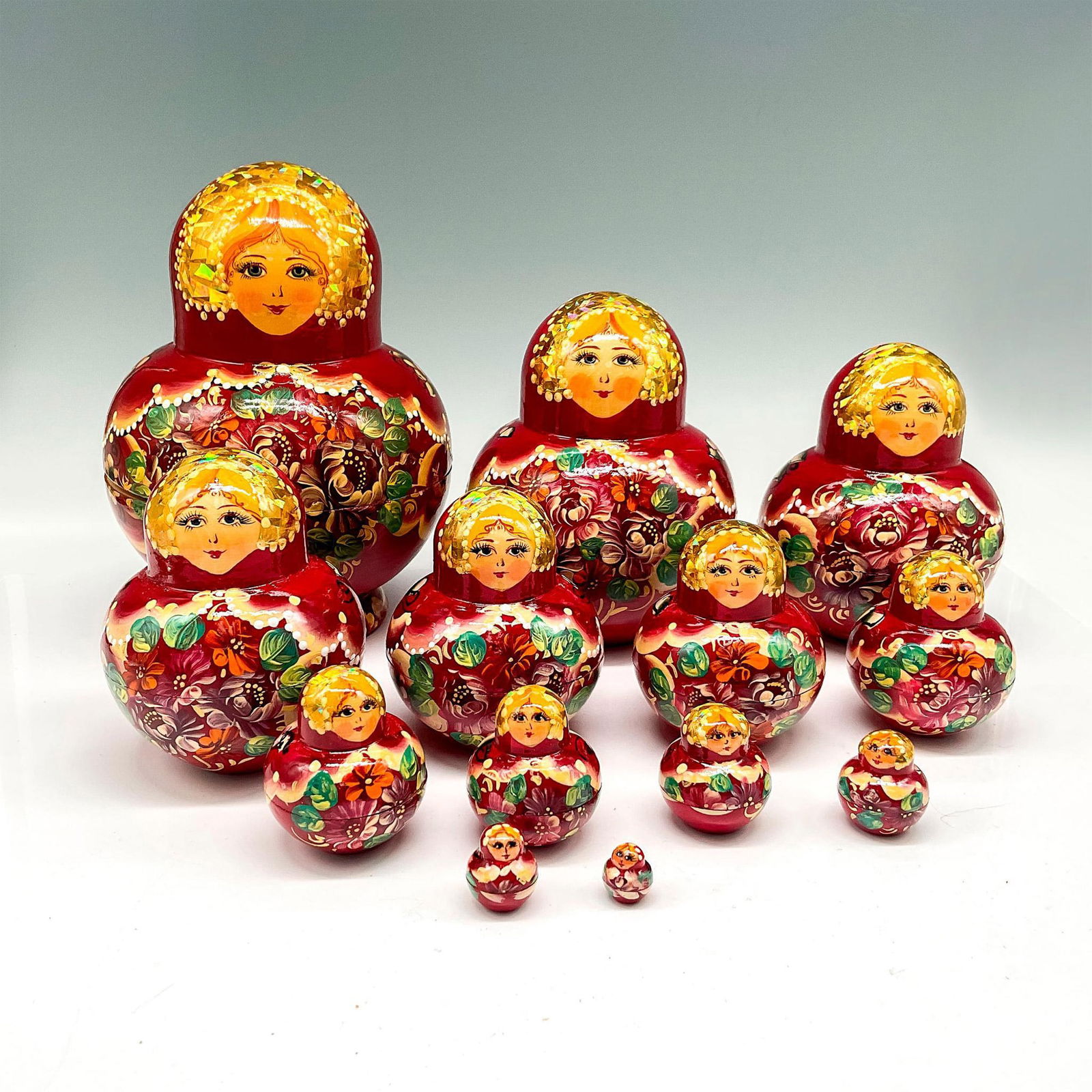 Vintage Lacquered Wood Russian Matryoshka Nesting Dolls: Intricately hand painted over red lacquer with gold toned iridescence and floral designs on 13 tiered dolls. Signed by artist. Issued: 20th century Dimensions: 7.25"H x 5" dia. Country of Origin: Russ