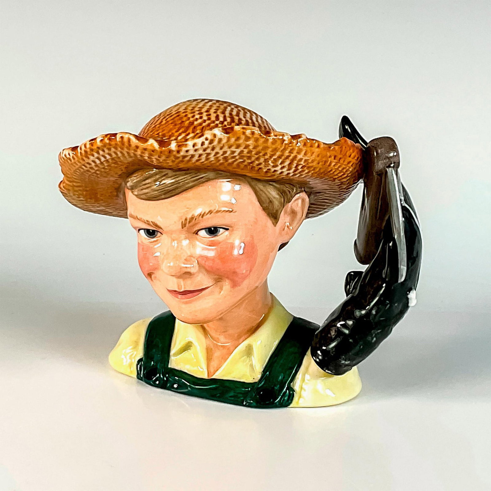Huckleberry Finn D7177 - Small - Royal Doulton Character Jug: White shirt; green overalls; straw hat. Royal Doulton and ICC backstamp. Artist: Shane Ridge Issued: 2002 - 2002 Dimensions: 5.25"H Manufacturer: Royal Doulton Country of Origin: England
