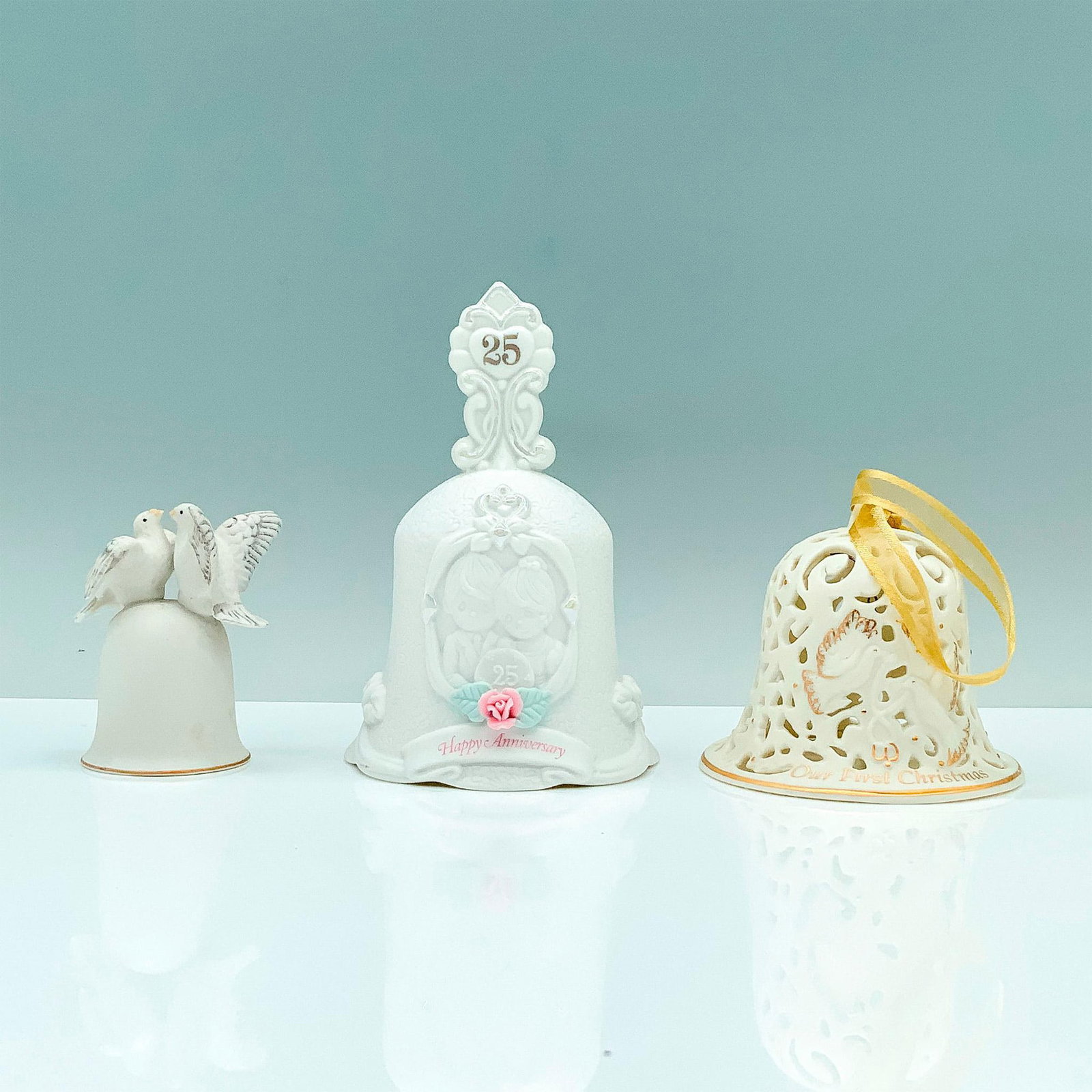 3pc Marriage Motif Dining Bells: A set of three white dining bells around the theme of marriage. A Wedgwood 2005 bell with two doves in the center with text that reads Our First Christmas. Wedgwood backstamp. An Enesco bell with a co