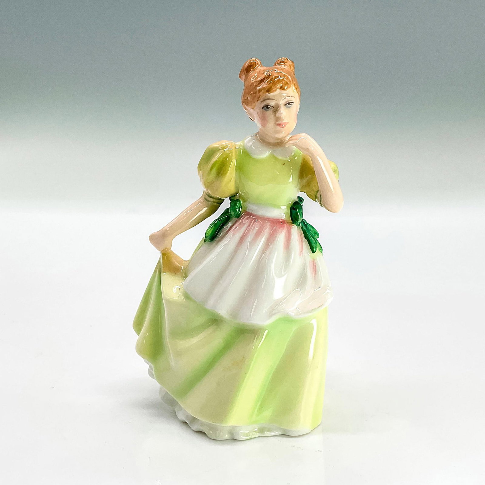 Young Melody HN3654 - Royal Doulton Figurine: Glazed bone china figure of young girl in a pale green dress holding the side of her skirt. Part of the Child Study series. Royal Doulton backstamp. Issued: 1994 Dimensions: 2.5"L x 2.25"W x 4.25"H Ma