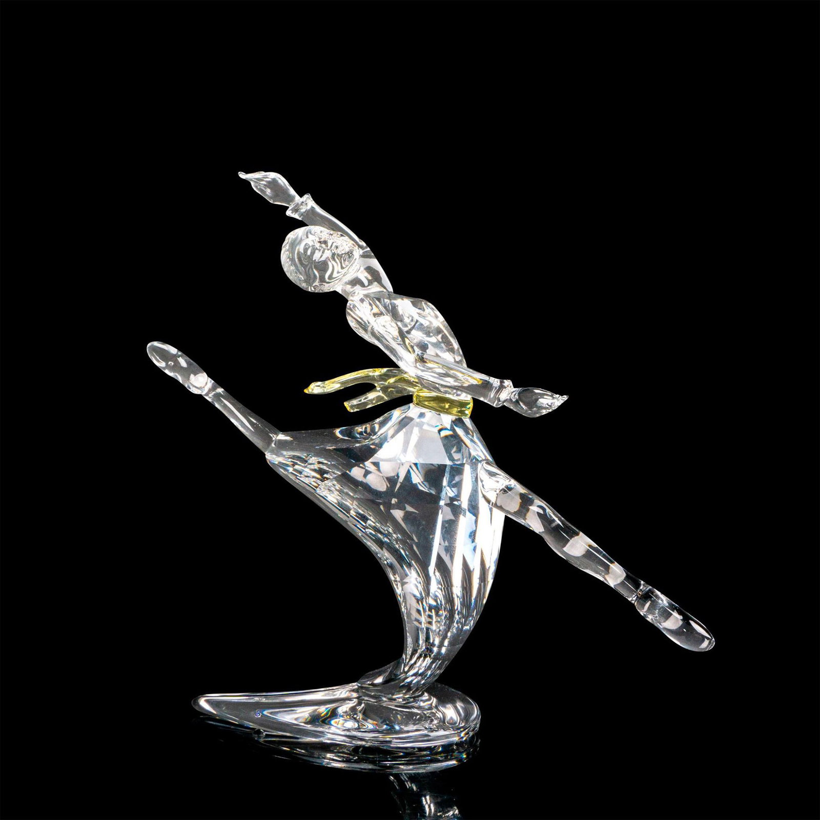 Swarovski Crystal Figurine, Anna + Base: Part of the Magic of Dance Trilogy. A clear crystal dancer with a pale yellow sash. Designed to represent Anna Pavlova. Swarovski markings on the figure. Includes base and certificate of authenticity.