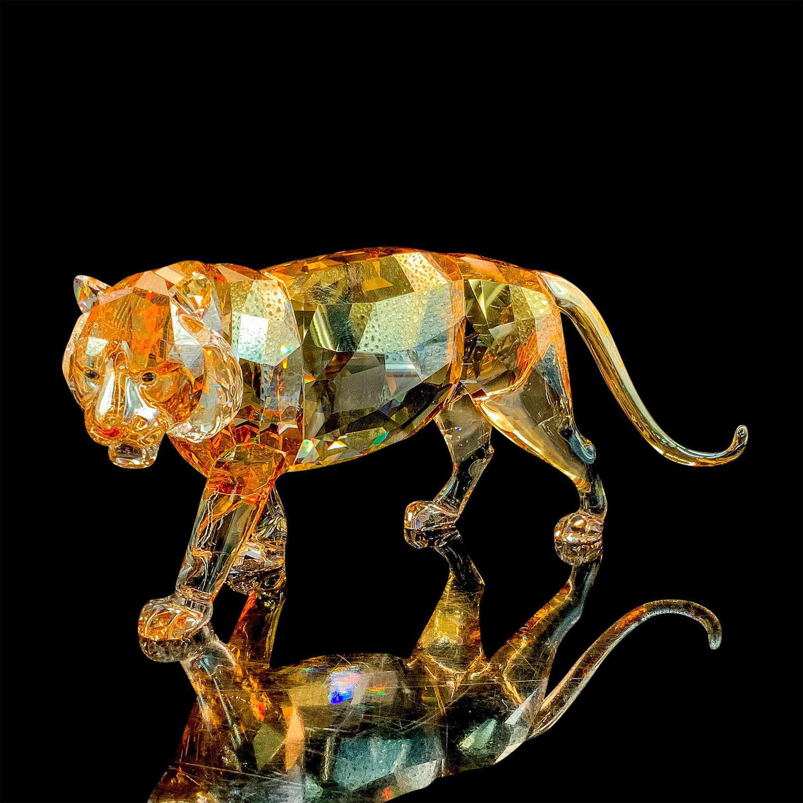 Swarovski Crystal Figurine, SCS Endangered Tiger: Shimmers in fully facetted golden shine crystal with satin crystal stripes; padparadscha crystal nose and moroda crystal eyes. Item has original box measuring 8.75"L x 8.75"W x 5"H. Artist: Elisabeth 