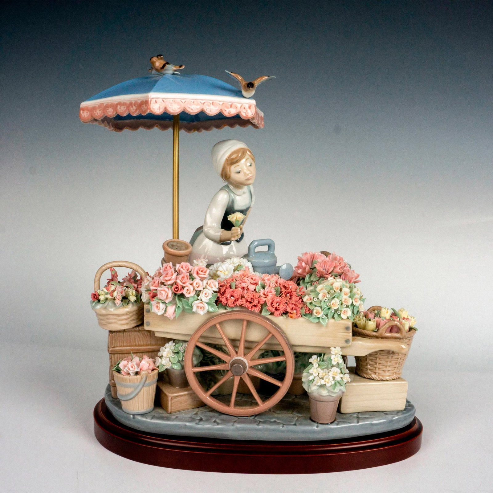 Flowers Of The Season 1001454 - Lladro Porcelain Figurine: Glossy finish; Lladro backstamp. Includes original box. Box measures: 17"L x 11.25"W x 14.5"H. Includes base. Base measures: 10.25"L x 7.25"W x 1"H. Artist: Jose Puche Issued: 1983 Dimensions: 11.75"H