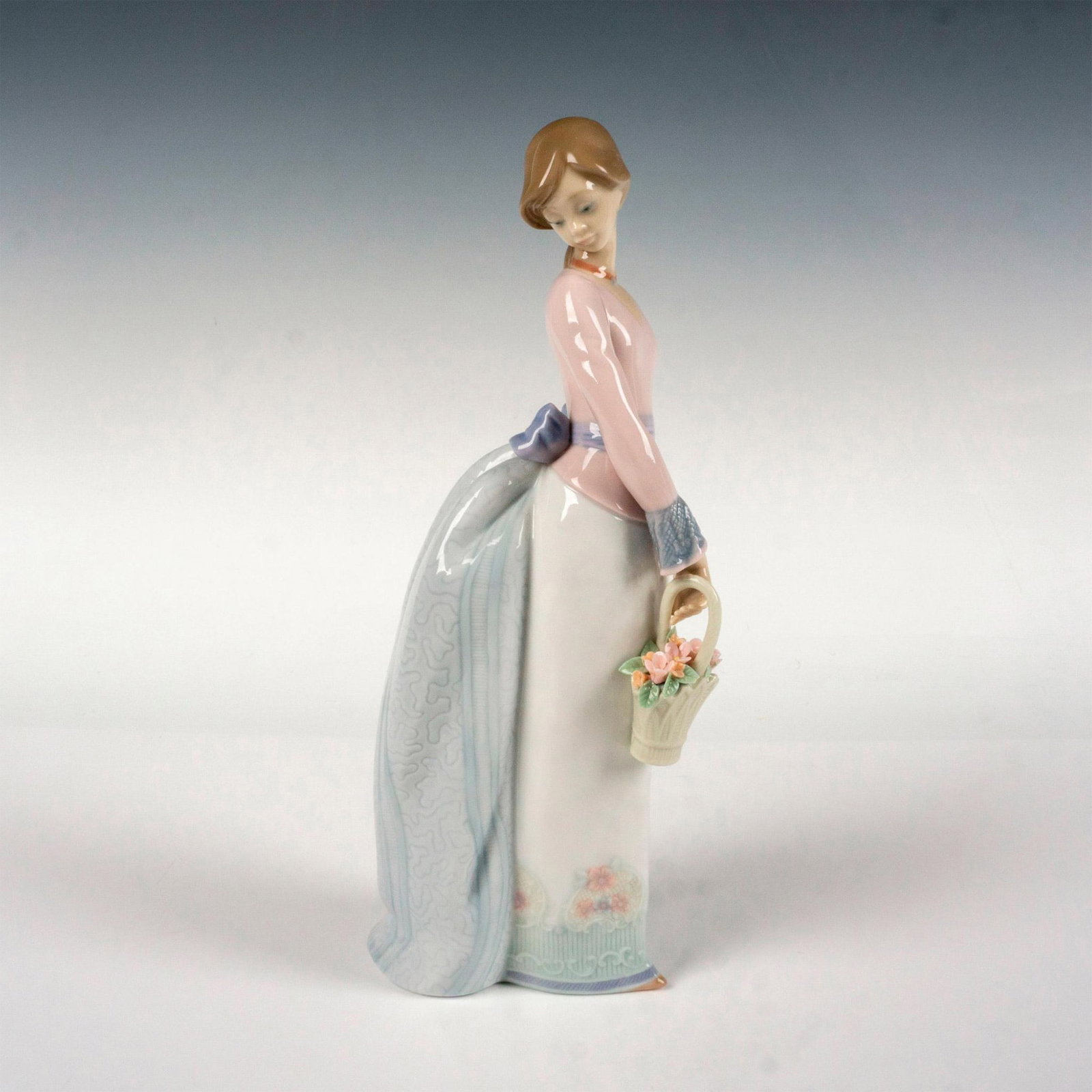 Basket Of Love 1007622 - Lladro Porcelain Figurine: Glossy finish; Lladro backstamp. Artist: Jose Puche Issued: 1994 - 1994 Dimensions: 9.75"H x 4"W Manufacturer: Lladro Country of Origin: Spain