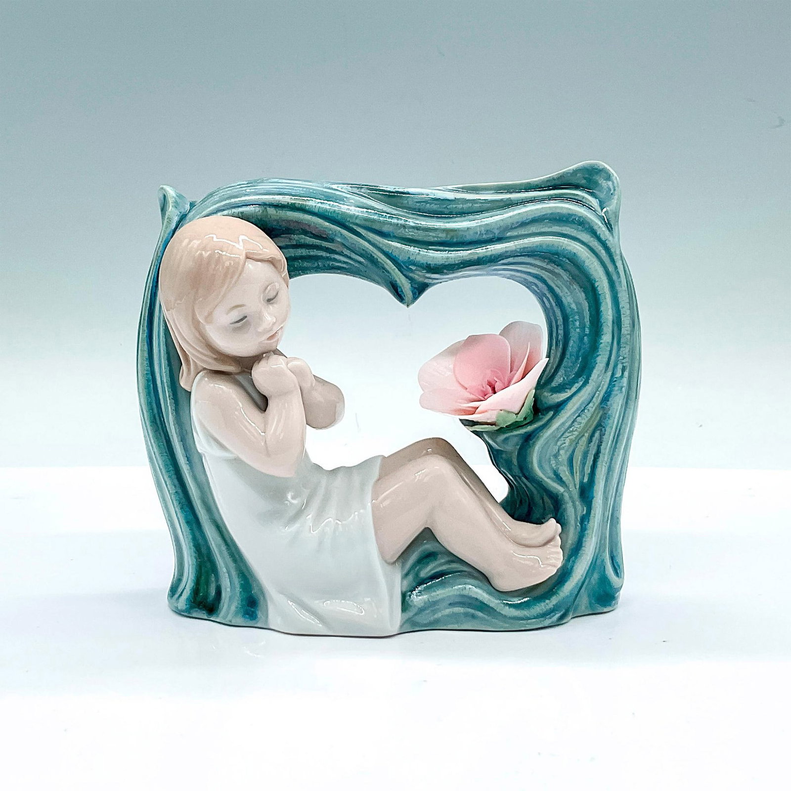 Childhood Fantasy 1008130 - Lladro Porcelain Figurine: A beautiful glossy figure of a young girl sleeping in a blue winding arch with a pink flower. Lladro backstamp. Artist: Marco Antonio Nogueron Issued: c. 2005-2008 Dimensions: 5.25"L x 2.5"W x 4.25"H 