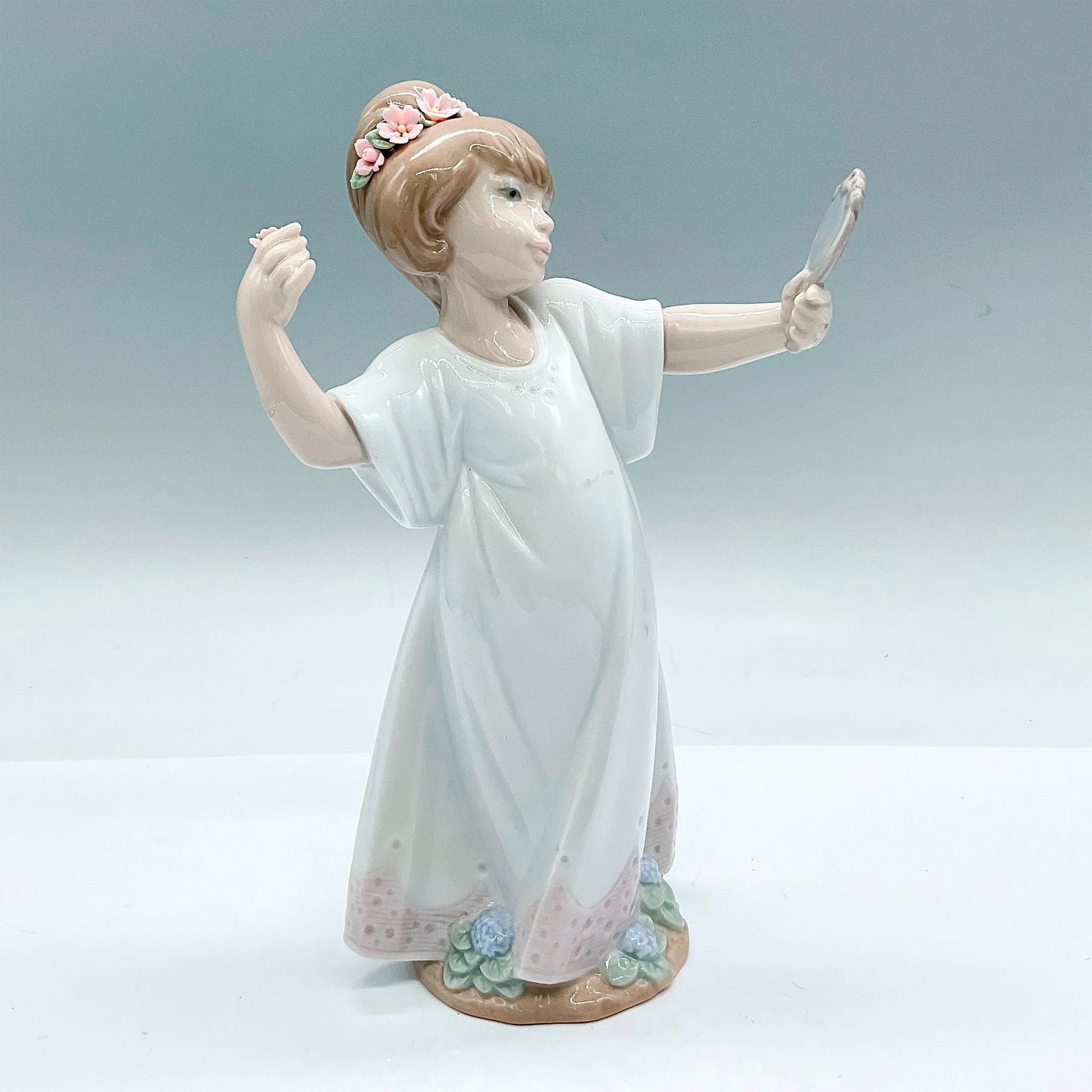 Delightful 1006806 - Lladro Porcelain Figurine: A glossy figure of a young girl admiring herself in a handheld mirror. Lladro backstamp. Artist: Juan Huerta Issued: c. 2001-2004 Dimensions: 5.25"L x 3.75"W x 9"H Manufacturer: Lladro Country of Ori