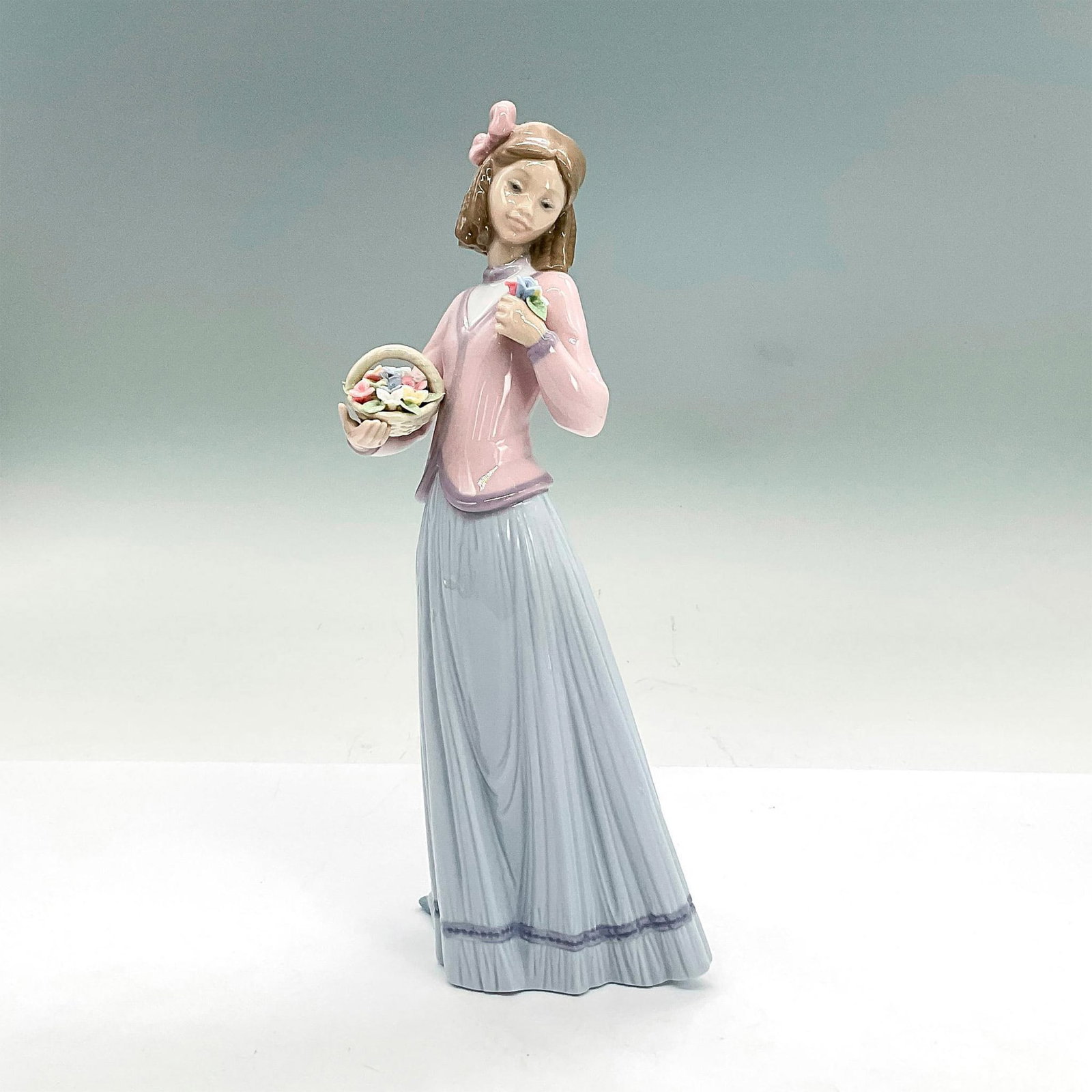 Innocence In Bloom 1007644 - Lladro Porcelain Figurine: Glossy finish; Lladro backstamp. Artist: Jose Puche Issued: 1996 - 1996 Dimensions: 9.75"H x 4.25"W Manufacturer: Lladro Country of Origin: Spain