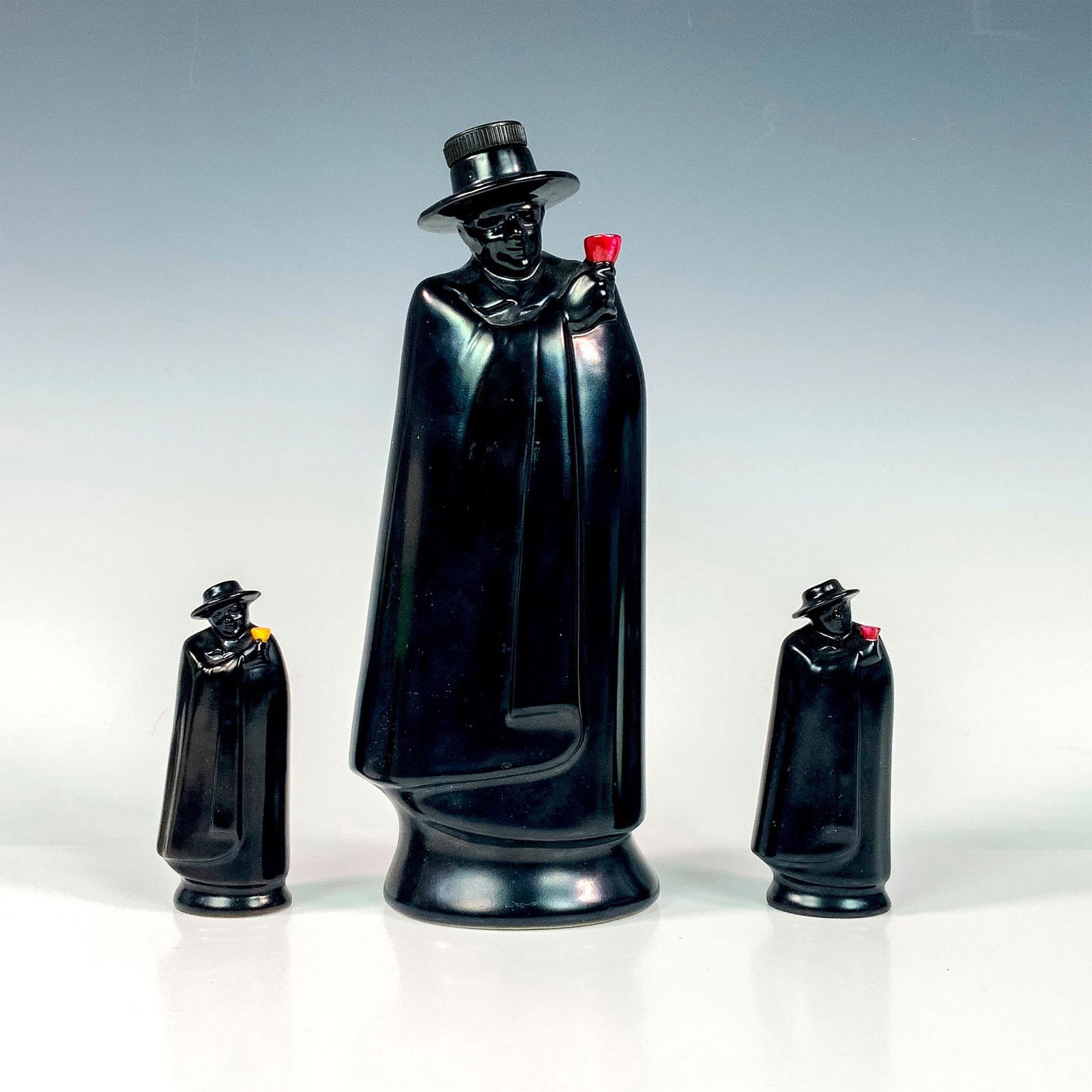 3pc Royal Doulton Sandeman Flasks: Sandeman Port Don Man with Black Cape figural decanters; red cup for Port, and the yellow cup for Sherry. Made for Geo Sandeman & Sons of London. Royal Doulton backstamp. Tallest measures: 4.25"L x 3"