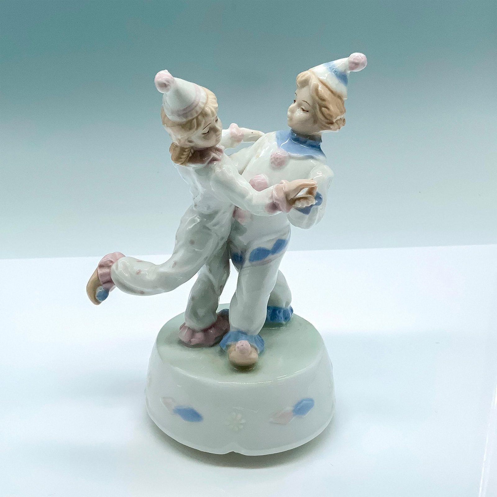 Meico Porcelain Dancing Clowns Music Box: Cute figurine of two young clowns dancing on top of a rotating platform. Glossy finish; Meico sticker on the bottom. Dimensions: 4.5"L x 4"W x 7.25"H