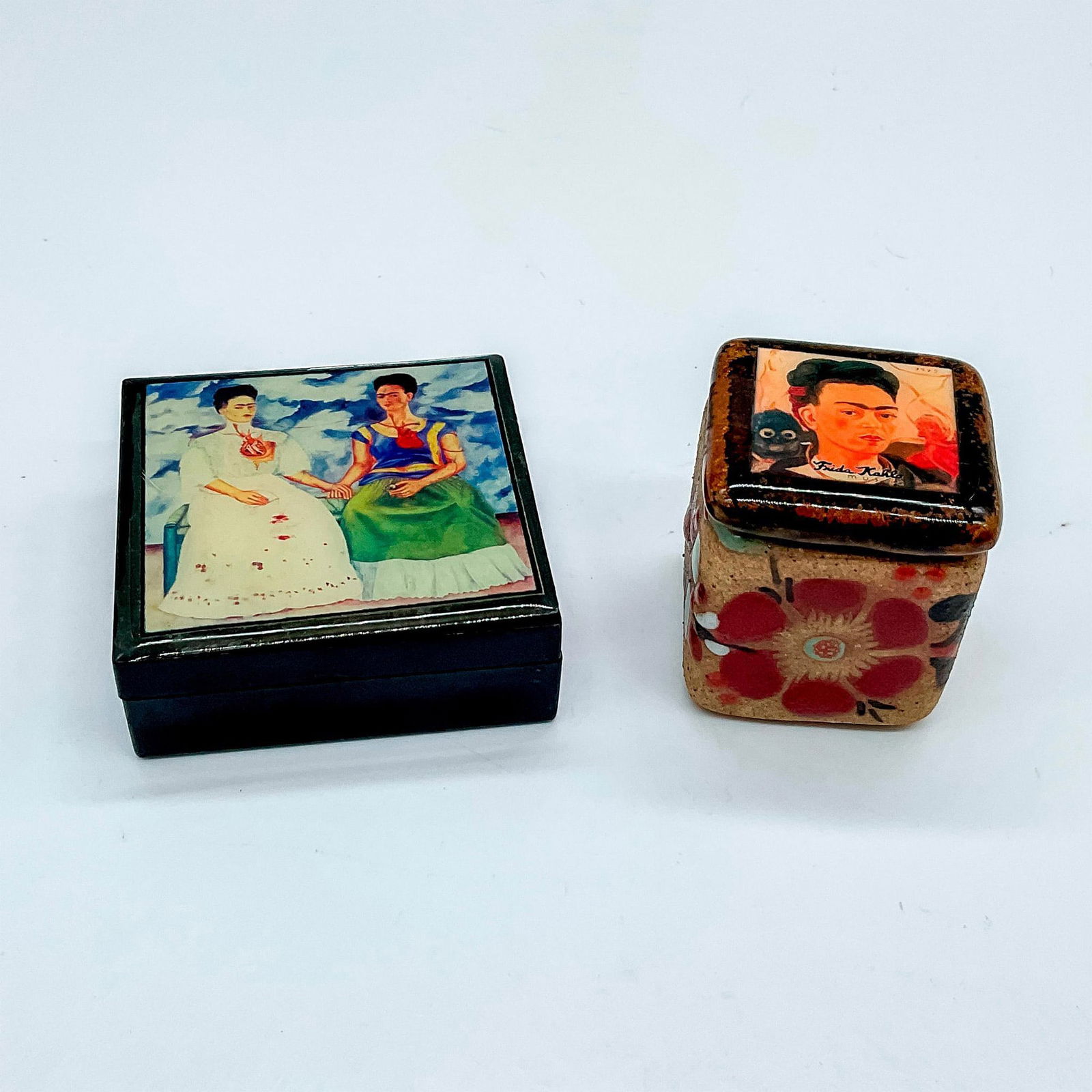 2pc Vintage Mexican Frida Kahlo Decorative Boxes: A collection of miniature boxes decorated with the photos of Frida Kahlo's self-portraits. One box is black resin featuring Las Dos Fridas on the cover. The other box is a floral painted pottery box w