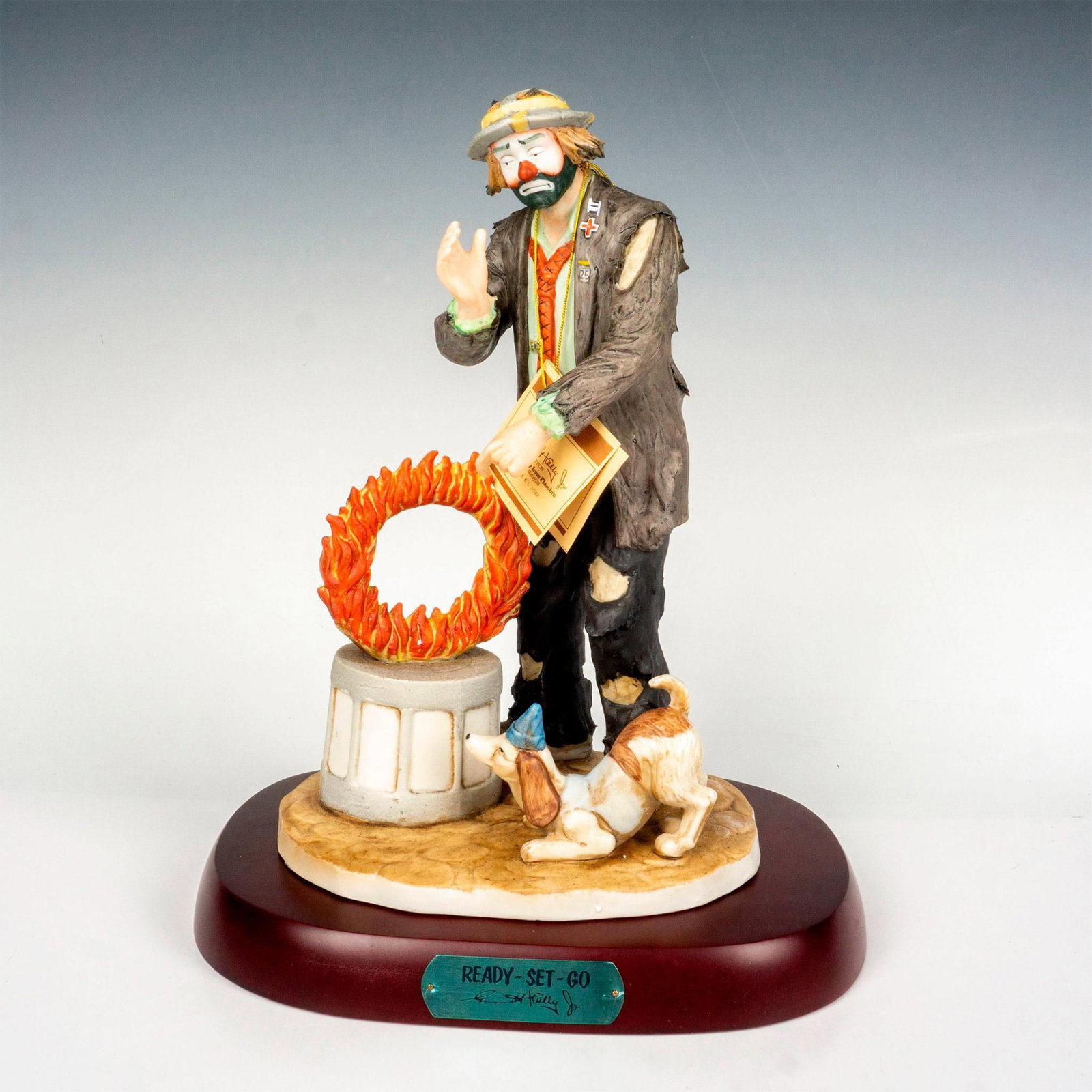 Flambro Emmett Kelly Jr. Figurine, Ready-Set-Go: Limited edition, hand painted bisque porcelain depicting figural clown Weary Willie practicing tricks with his dog. Rests on a wooden base with gold-tone titled plaque. Emmett Kelly Jr. signature back