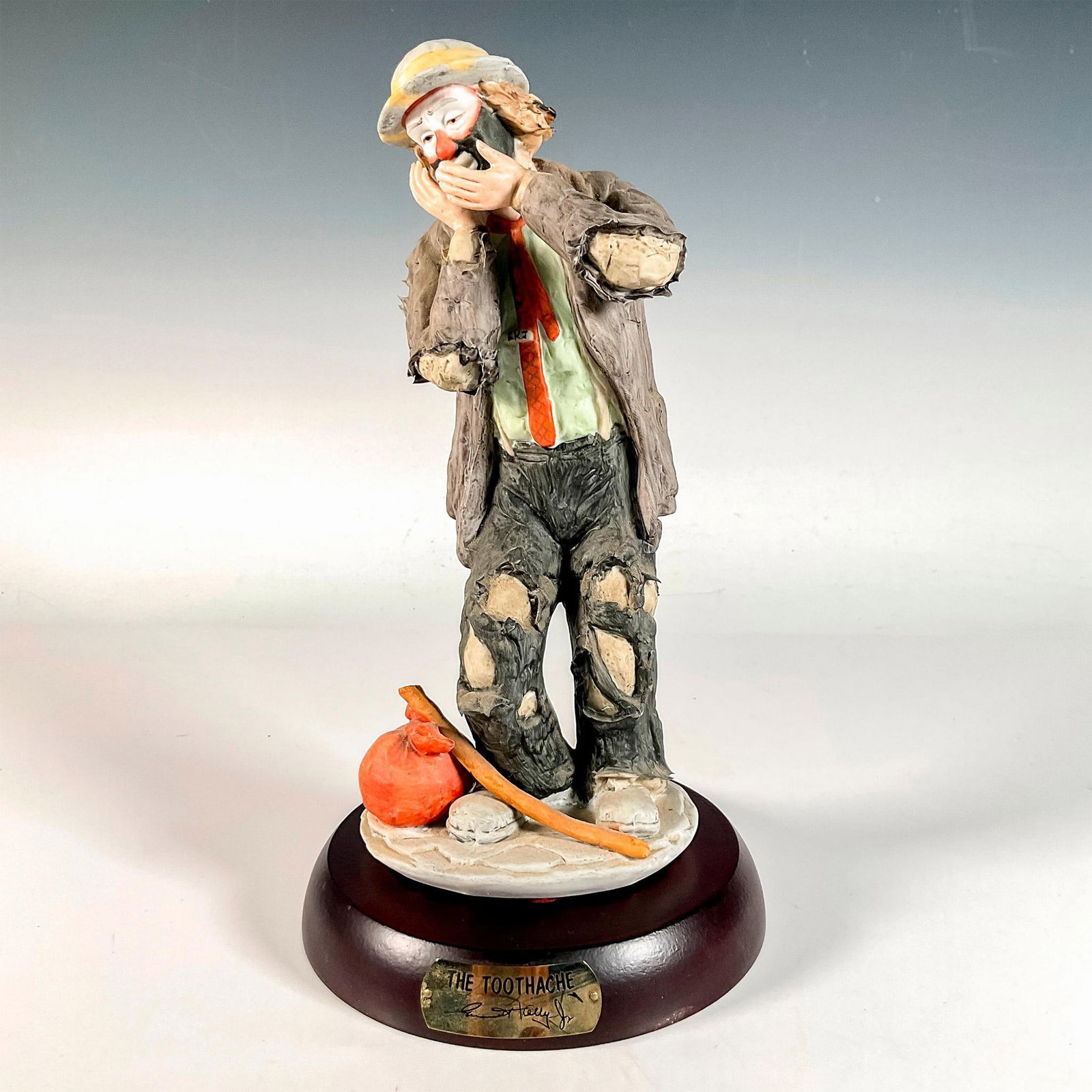 Flambro Emmett Kelly Jr. Figurine, The Toothache: Limited edition, hand painted bisque porcelain depicting figural clown Weary Willie hand covering mouth with a toothache. Rests on a wooden base with gold-tone titled plaque. Emmett Kelly Jr. signatur