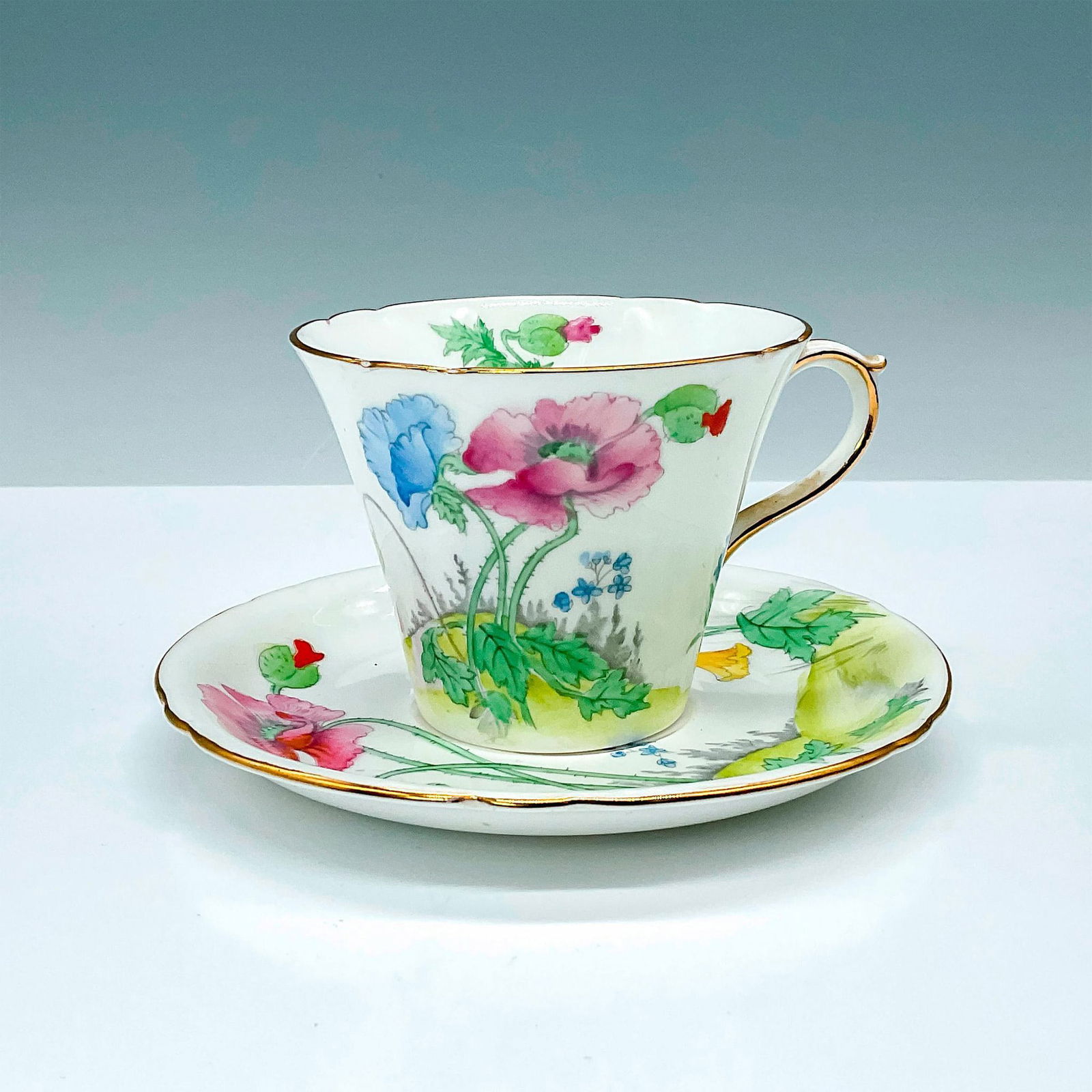 Shelley China Teacup and Saucer Set, Poppies: Lovely teacup and matching saucer set of beautiful white bone china decorated with multi-colored poppy flowers finished with gold trim. Pattern number 0260. Shelley backstamps. Cup: 4.25"L x 3.5"W x 2
