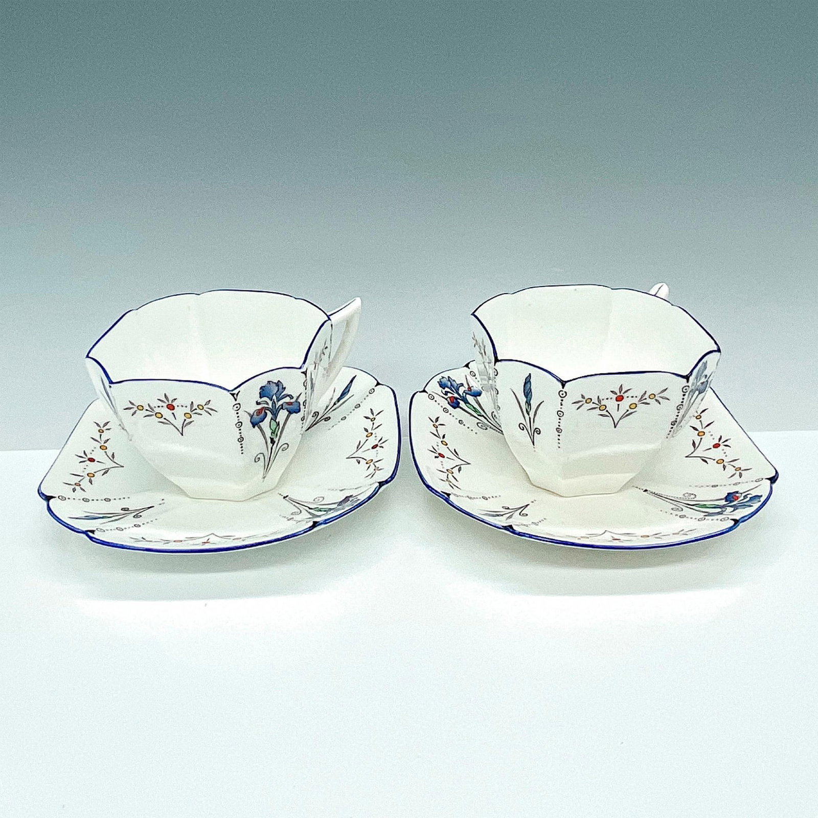 Pair of Shelley Fine Bone China Teacups w/Saucers, Blue Iris: Stunning Blue Iris porcelain teacups with their saucers in Queen Anne Shape. Shelley backstamp. Issued: 20th Century Dimensions: 6" x 4.25"W x 0.75"H Manufacturer: Shelley Country of Origin: England