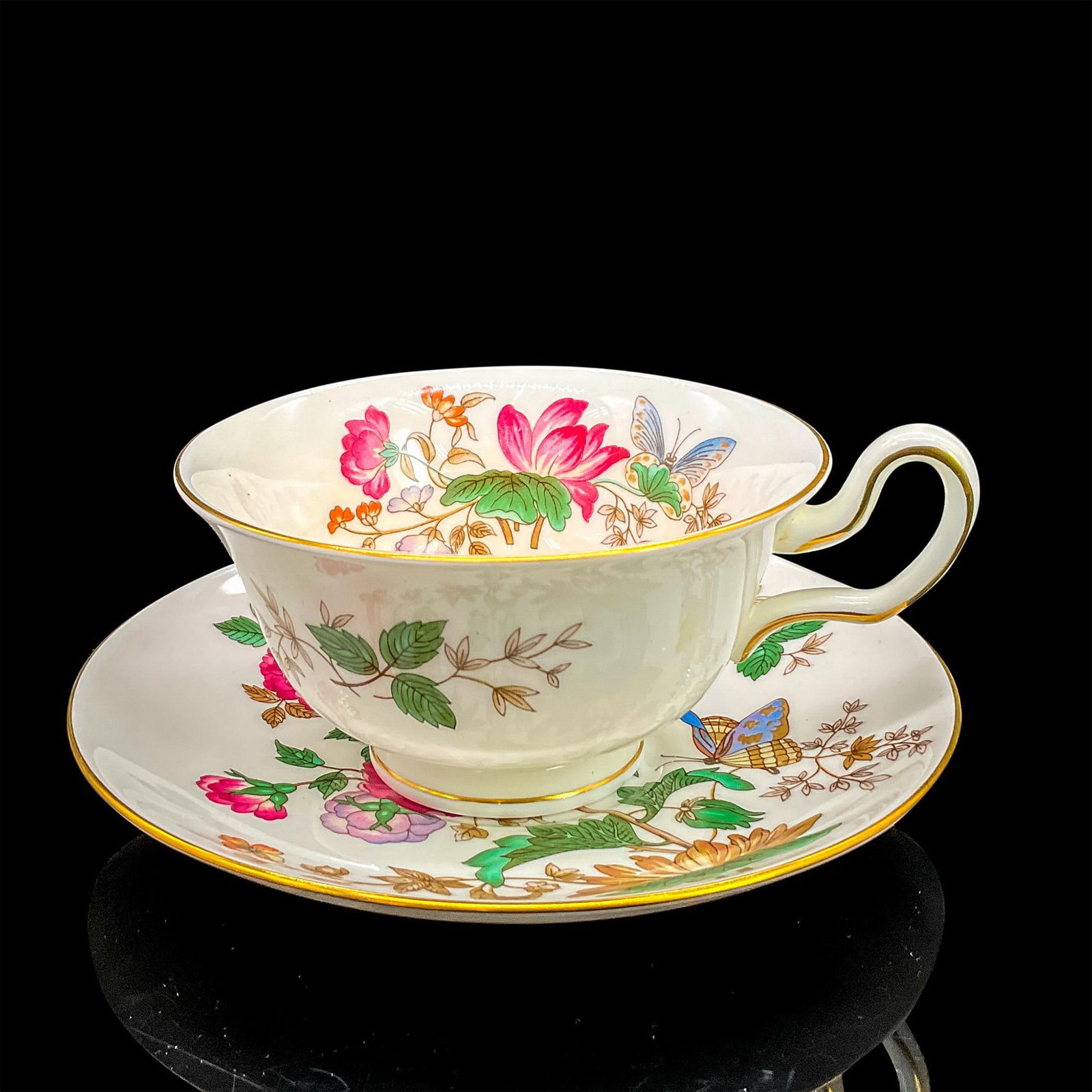 Wedgwood Cup and Saucer, Charnwood: Bone china tea cup and saucer with a dark pink flowers and butterflies design; gilt rims. Wedgwood backstamp. Cup 5"L x 4"W x 2.25"H. Saucer 0.75"H x 5.75" dia. Manufacturer: Wedgwood Country of Origi