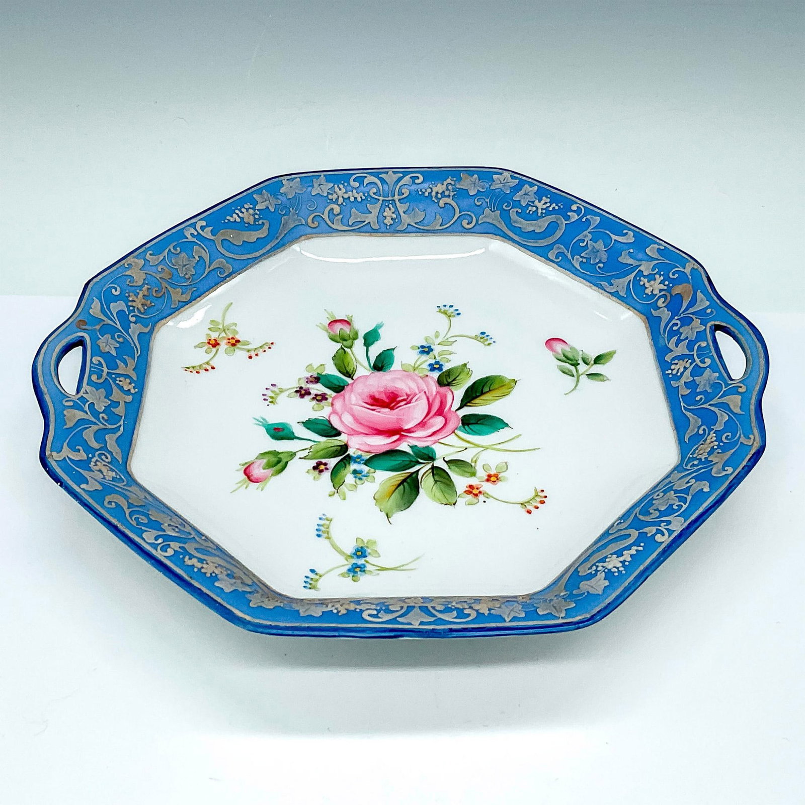 Nippon Bone China Double Handled Dish, Floral: Lovely octagonal double handled dish decorated with colorful roses finished with a beautiful raised white embellishment over a stunning blue edge. Nippon Hand Painted backstamp marked to base. Issued: