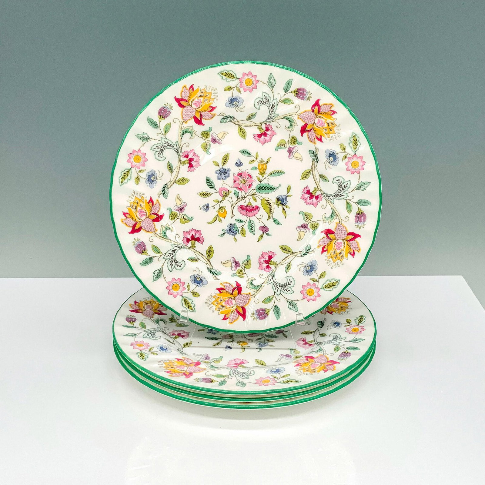 4pc Minton Haddon Hall Bone China Floral Plates: A set of 4 plates painted with green borders and beautiful springtime flowers for the design. Minton backstamp. Dimensions: 0.25"H x 8" dia. Manufacturer: Minton Country of Origin: England