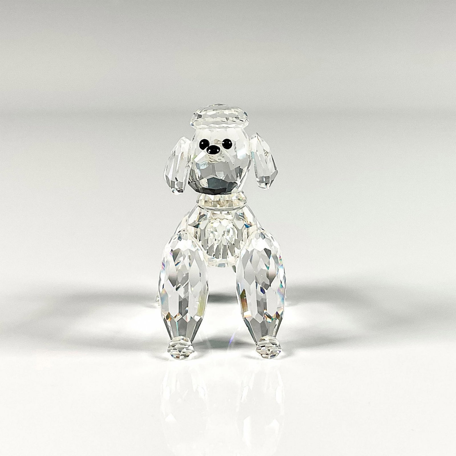 Swarovski Crystal Figurine, Poodle Standing: Lead crystal part of the Pets Corner collection and is made with jet crystal eyes and nose. Swarovski etched backstamp. This item has its original box. Box measures: 5"W x 3.75"H. Artist: Adi Stocker 