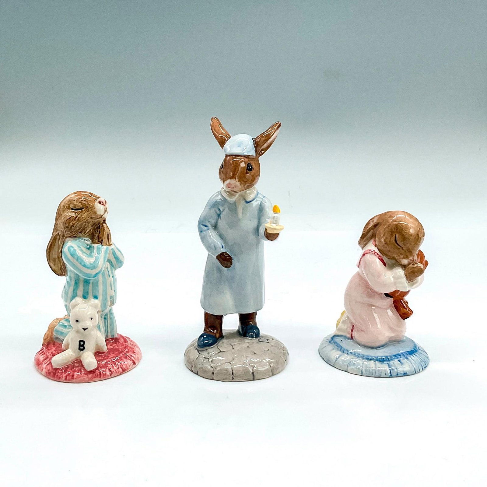 3pc Royal Doulton Bunnykins Figurines, Bedtime: Three glazed bone china figures of rabbits getting ready for bed. Wee Willie Winkie DB270, Bedtime DB79 and Goodnight DB157. Royal Doulton backstamp. Wee Willie Winkie is the tallest 2.25"L x 2"W x 4.