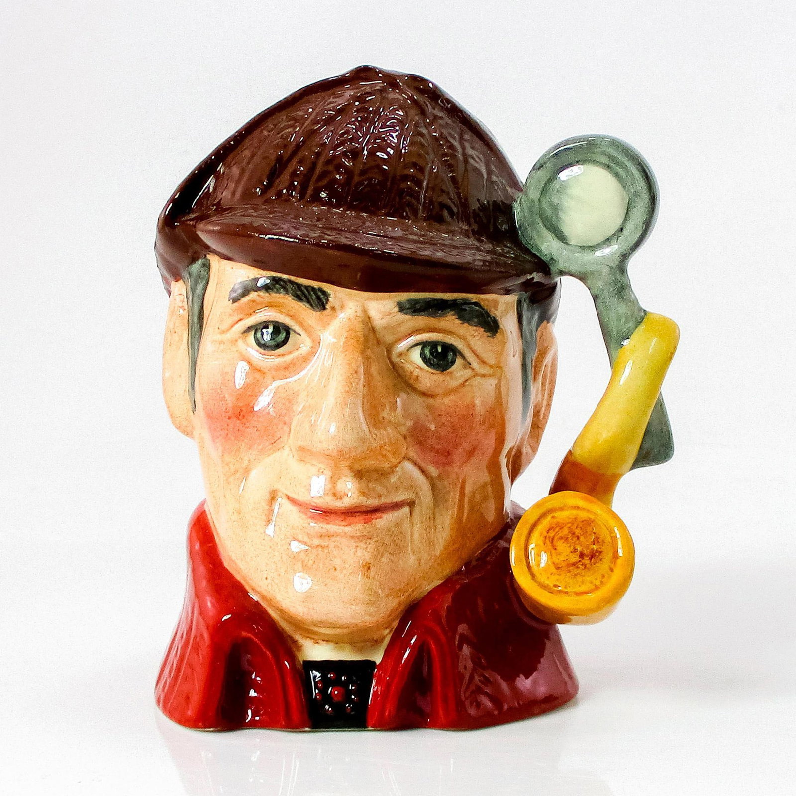 Sleuth D6773 (Colorway) - Small - Royal Doulton Character Jug: Variation Two. Brown deerstalker hat; red cloak. Arthur Conan Doyle (1859 - 1930), an unsuccessful doctor, published the first of his widely popular detective stories in 1887. The amateur sleuth Sherl