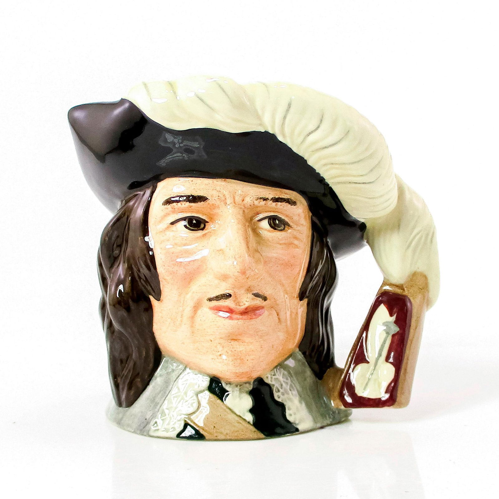 D'Artagnan D6764 - Small - Royal Doulton Character Jug: Black hat trimmed with white feathers; white lace collar. A character in Alexandre Dumas' lively 19th-century fiction. D'Artagnan came to Paris to join the celebrated band of Three Musketeers and shar