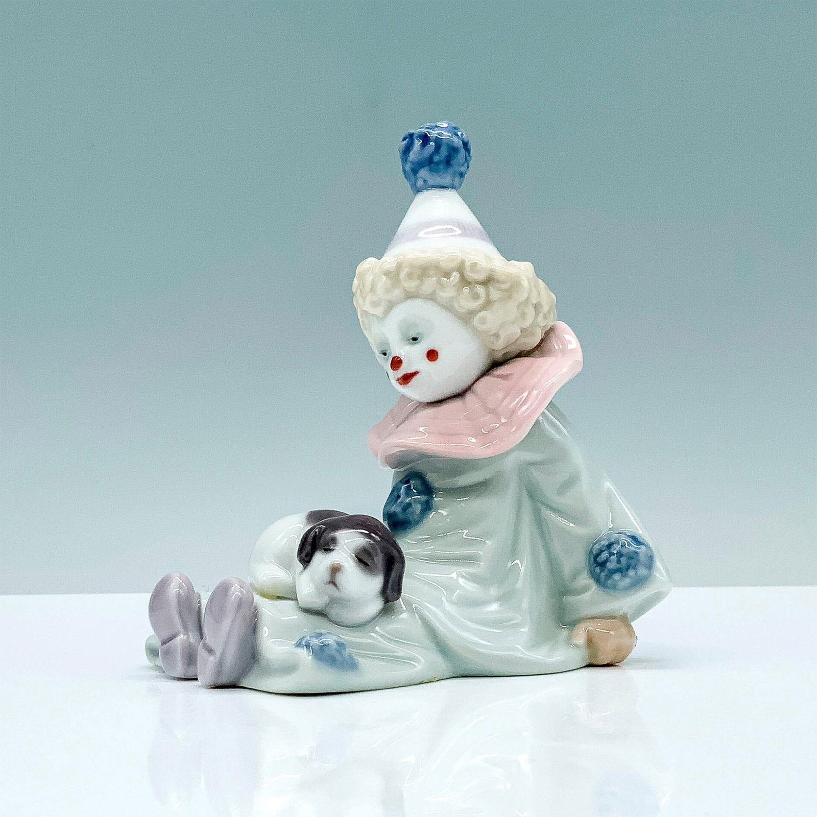 Pierrot With Puppy 1005277 - Lladro Porcelain Figurine: Glossy finish; Lladro backstamp. Artist: Jose Puche Issued: 1985 - 2007 Dimensions: 4.5"H x 3.5"W Manufacturer: Lladro Country of Origin: Spain