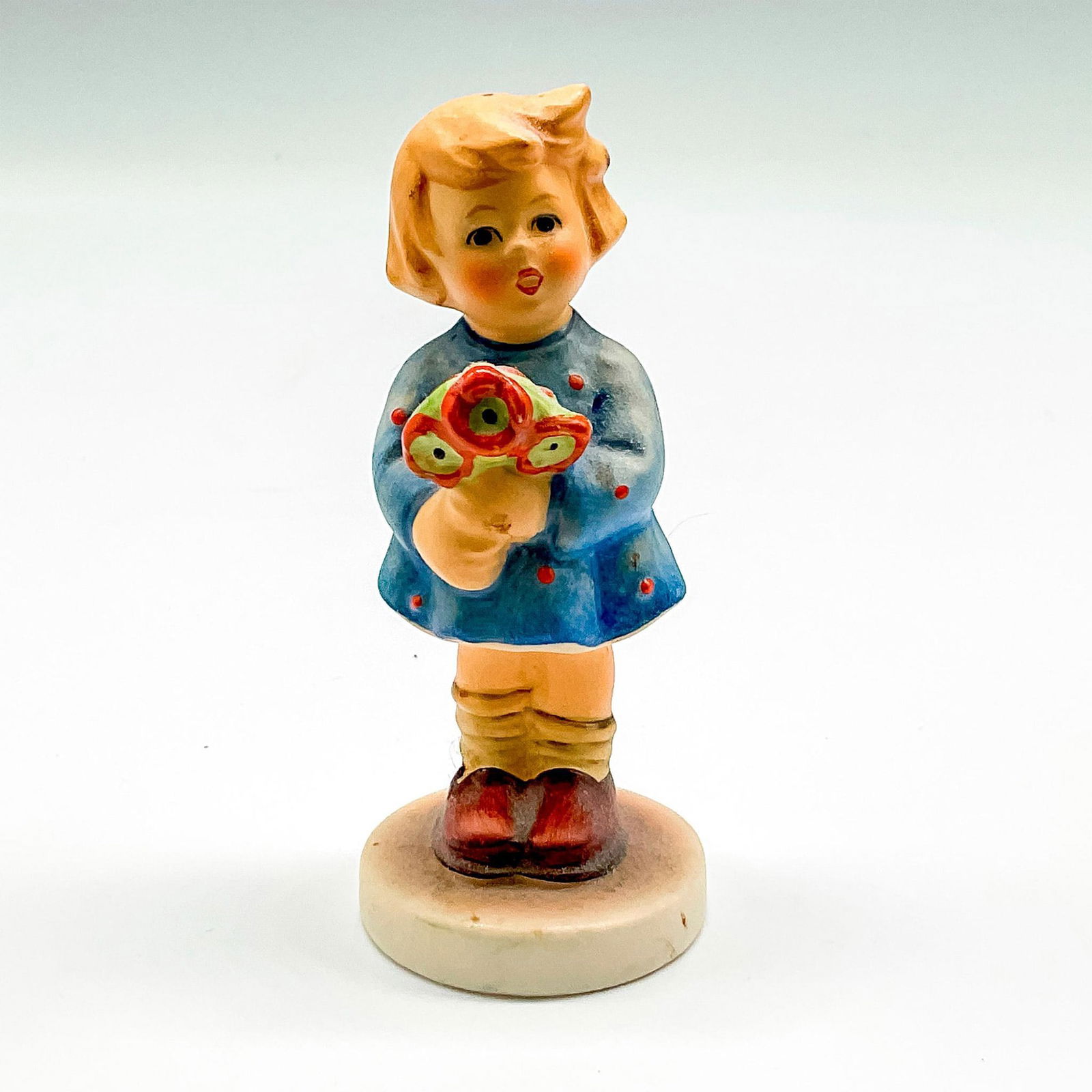 Goebel Hummel Porcelain Figurine, Girl with Nosegay: Hand painted figural holding orange and green flowers colored in blue dress. Goebel backstamp. Hummel impressed mark. 239A. Issued: 1967 Dimensions: 3.5"H x 1.25" dia. Manufacturer: Goebel Hummel Coun