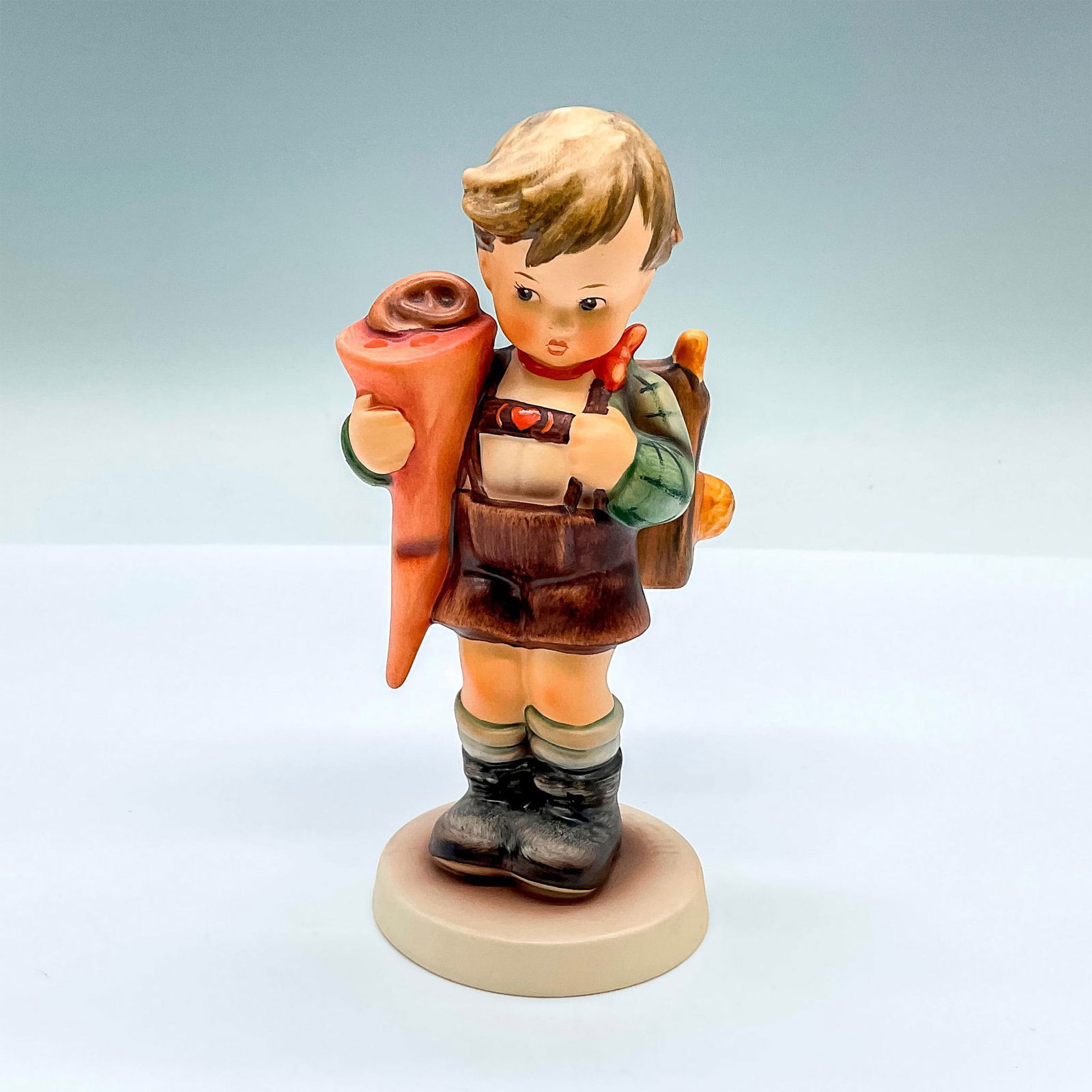 Goebel Hummel Porcelain Figurine, Little Scholar HUM 80: Hand painted figure of a young boy with a backpack. Goebel backstamp. Artist: M.I. Hummel Issued: 1993 Dimensions: 2.75"L x 2.75"W x 5.5"H Manufacturer: Goebel Hummel Country of Origin: Germany