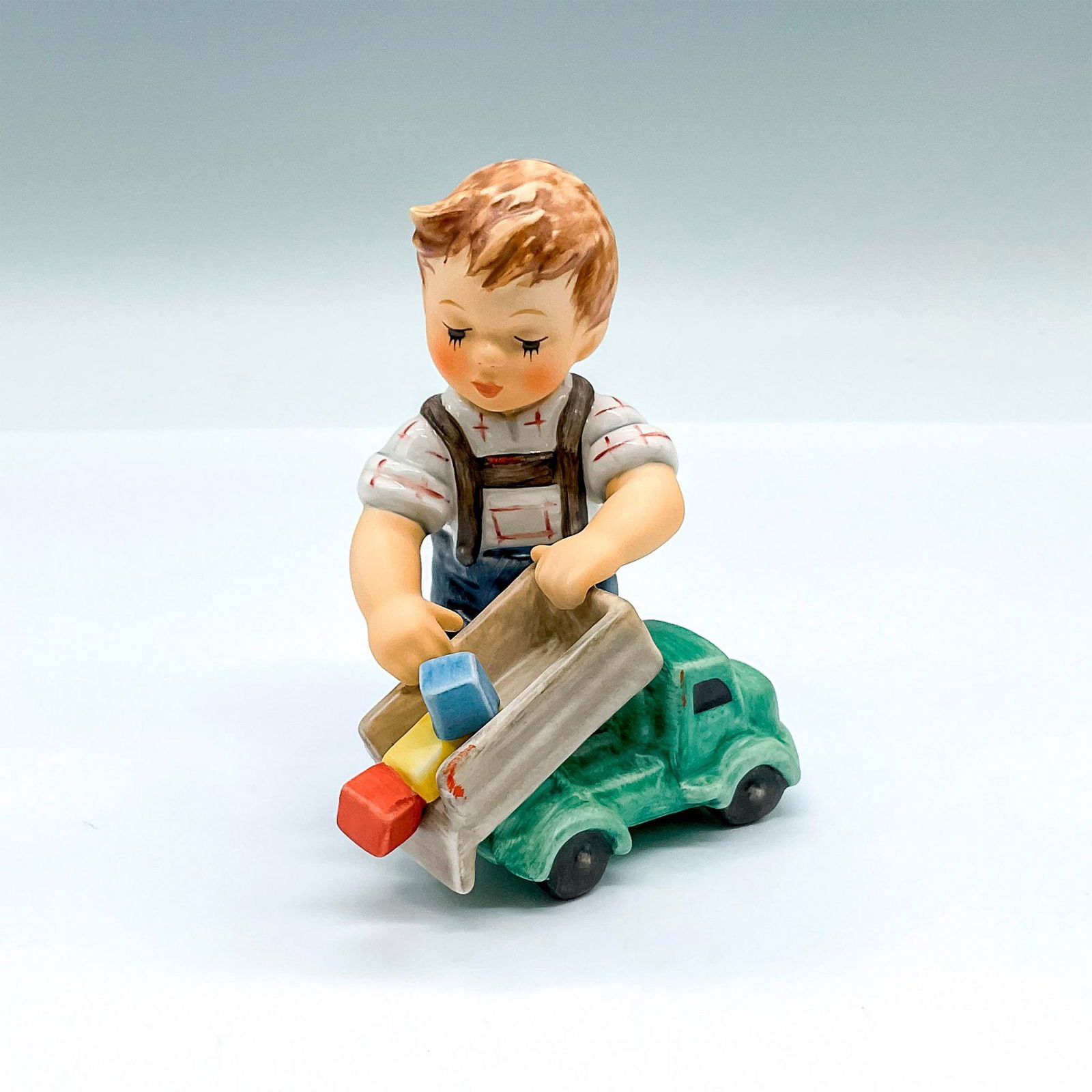 Goebel Hummel Porcelain Figurine, Loads Of Fun HUM 2156: Hand painted figure of a young boy playing with a toy dump truck. Goebel backstamp. Artist: M.I. Hummel Issued: 2008 Dimensions: 4"L x 3"W x 4"H Manufacturer: Goebel Hummel Country of Origin: Ger