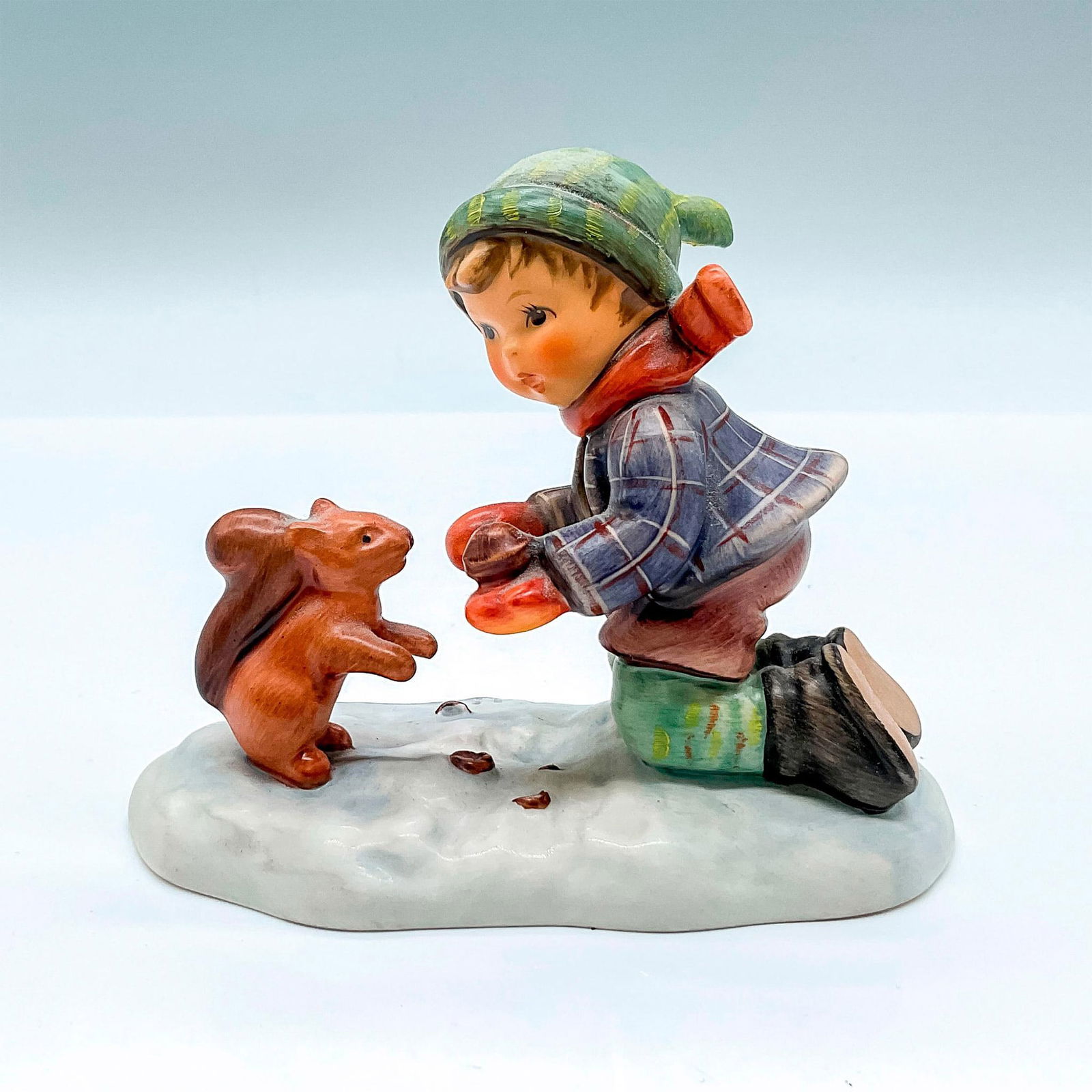 Goebel Hummel Porcelain Figurine, Playful Pals HUM 2053: Limited edition hand painted figure of a young boy feeding a squirrel. Goebel backstamp. Artist: M.I. Hummel Issued: 1998 Dimensions: 4.25"L x 2.5"W x 3.5"H Edition Number: 14702 of 25000 Manufacturer