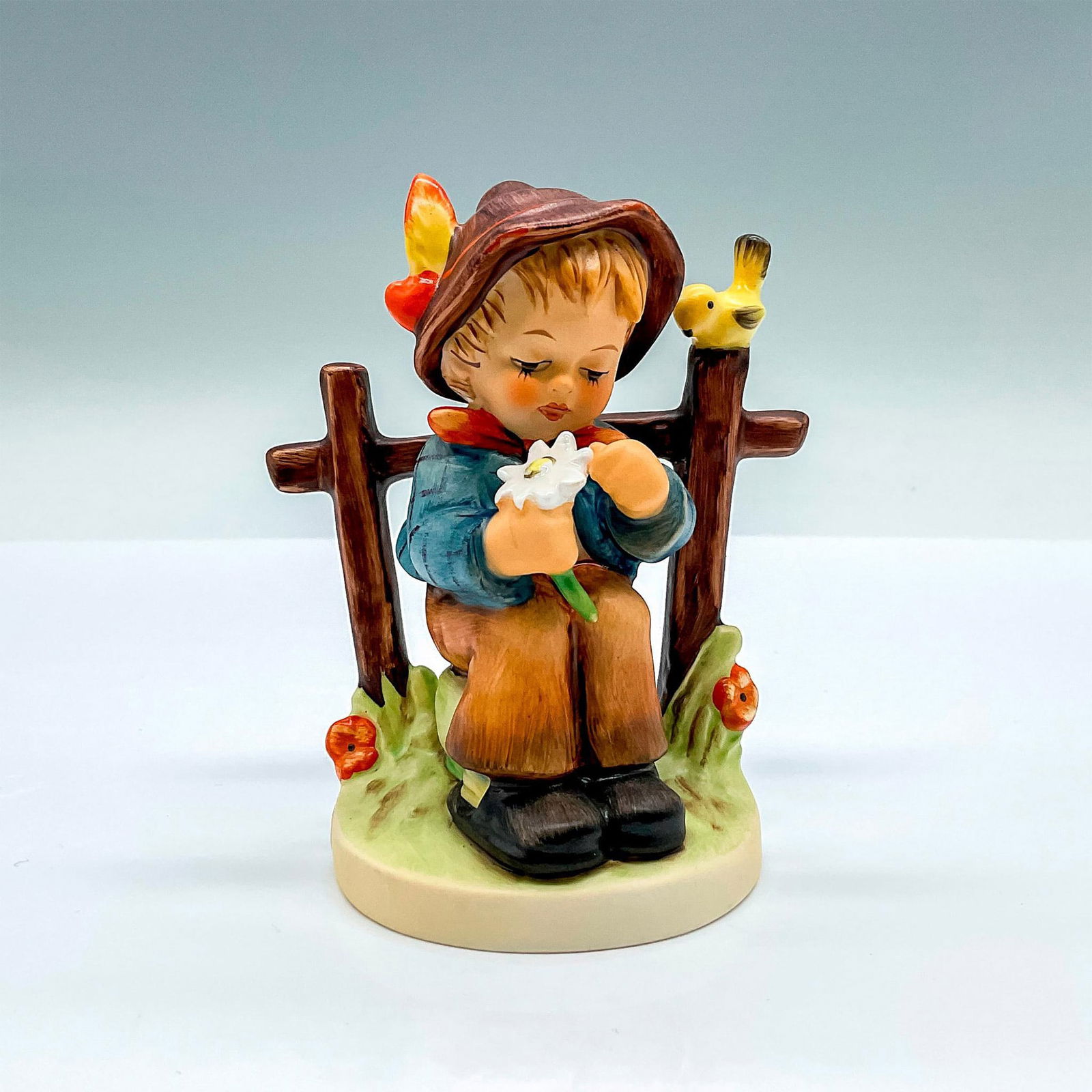 Goebel Hummel Figurine, She Loves Me, She Loves Me Not: HUM 147; hand painted porcelain figure of a young boy plucking petals from a white flower. Goebel backstamp. Artist: M.I. Hummel Issued: 2000 Dimensions: 3.5"L x 2.5"W x 4.25"H Manufacturer: Goebel Hu