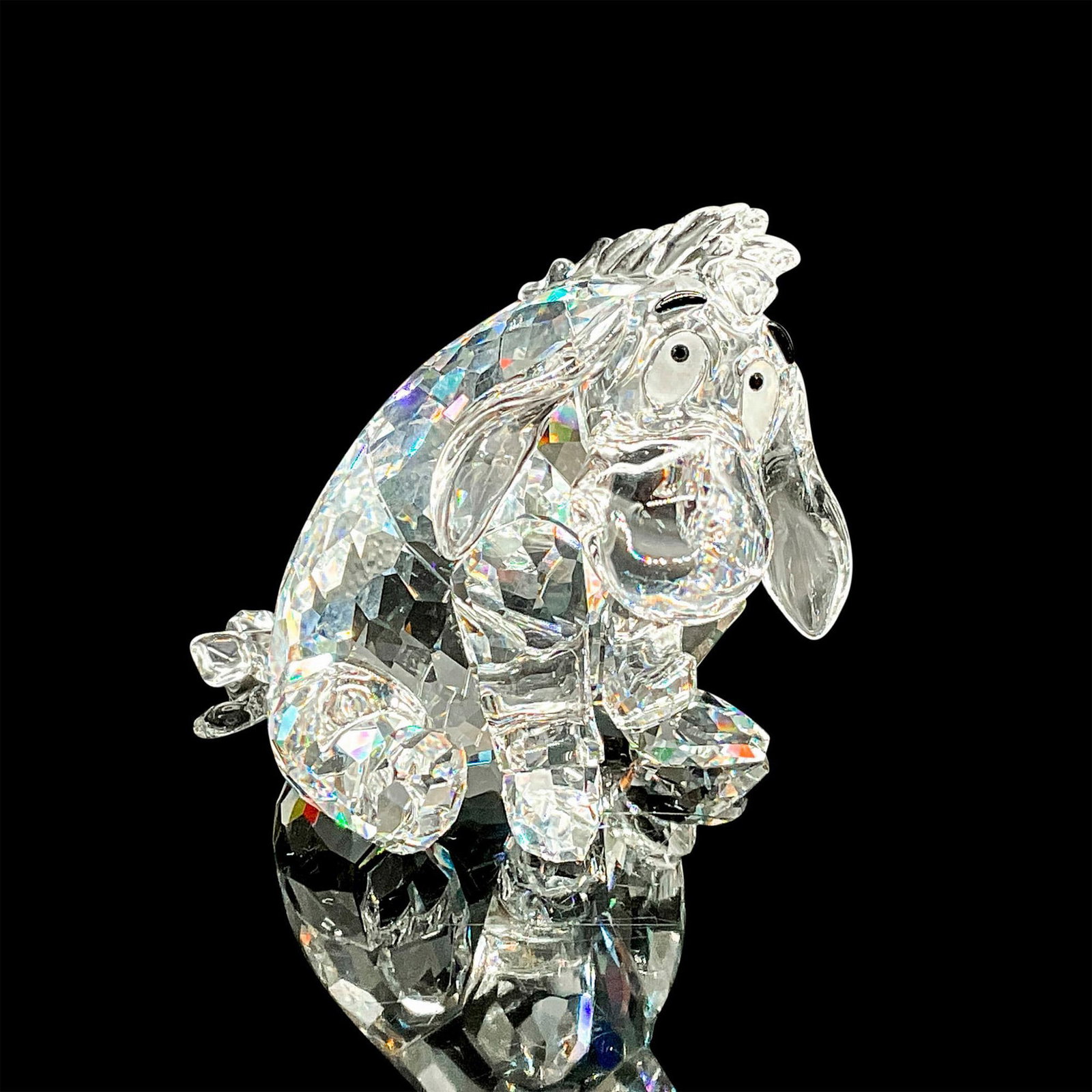 Swarovski Crystal Figurine, Eeyore: The famously gloomy character from Winnie the Pooh. This Swarovski figurine depicts Eeyore seated, featuring a faceted clear crystal body with unfaceted clear crystal face, ears, and tail. His eyes an
